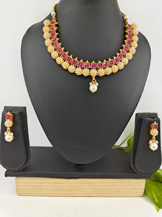 Gold finish set with red/ clear stones set in square design,embedded pearl balls at the bottom complete the set.