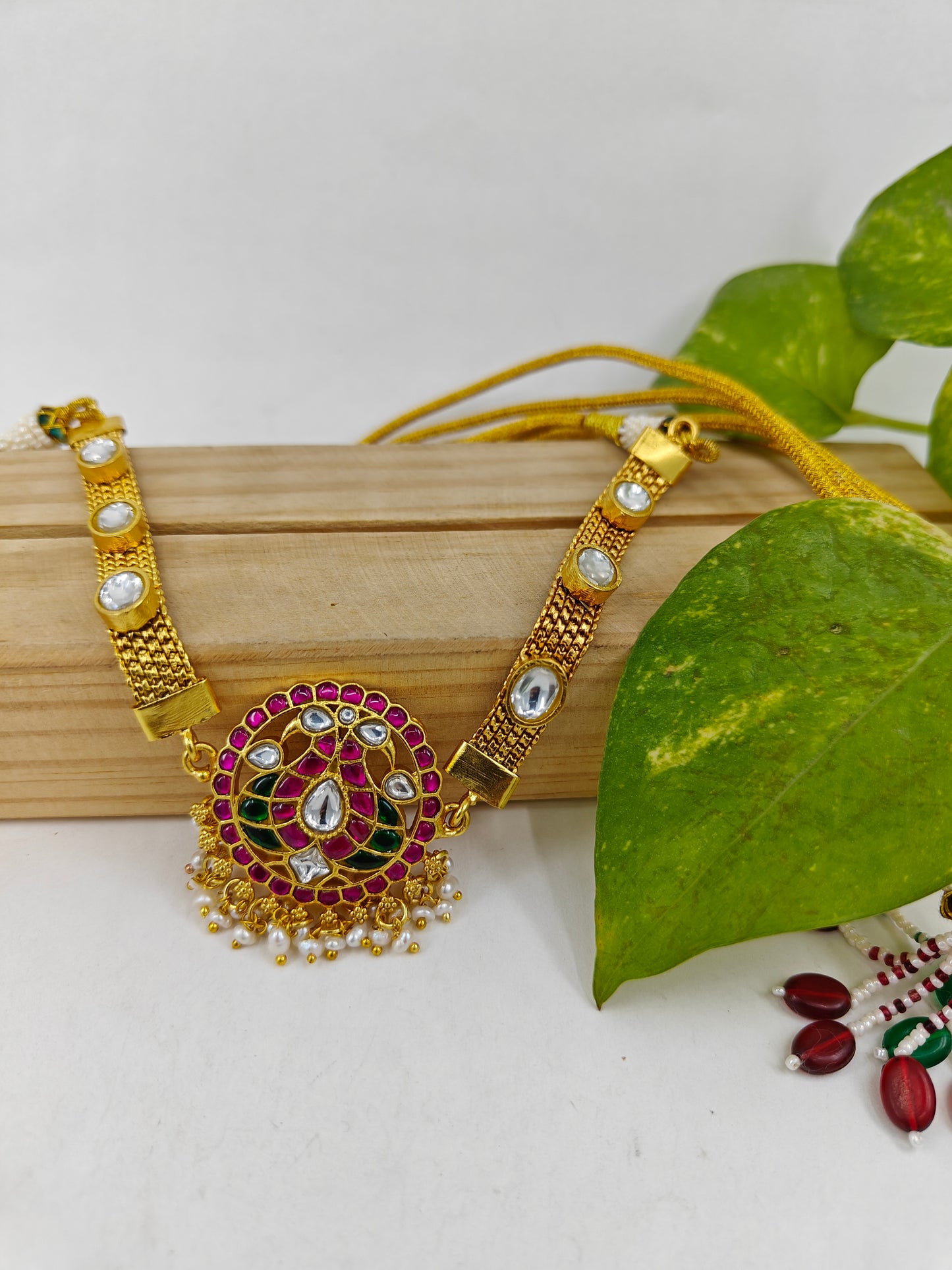 Necklace in gold finish with red and green Kemp stone inlay in peacock motif