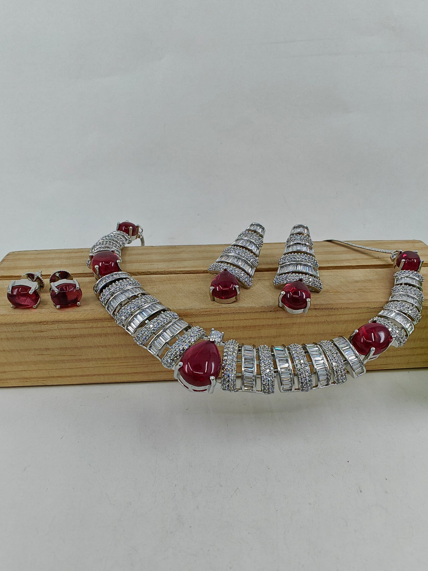 Set in platinum finish with CZ in alternate bands and ruby red stones.Comes with 2 pairs of earrings