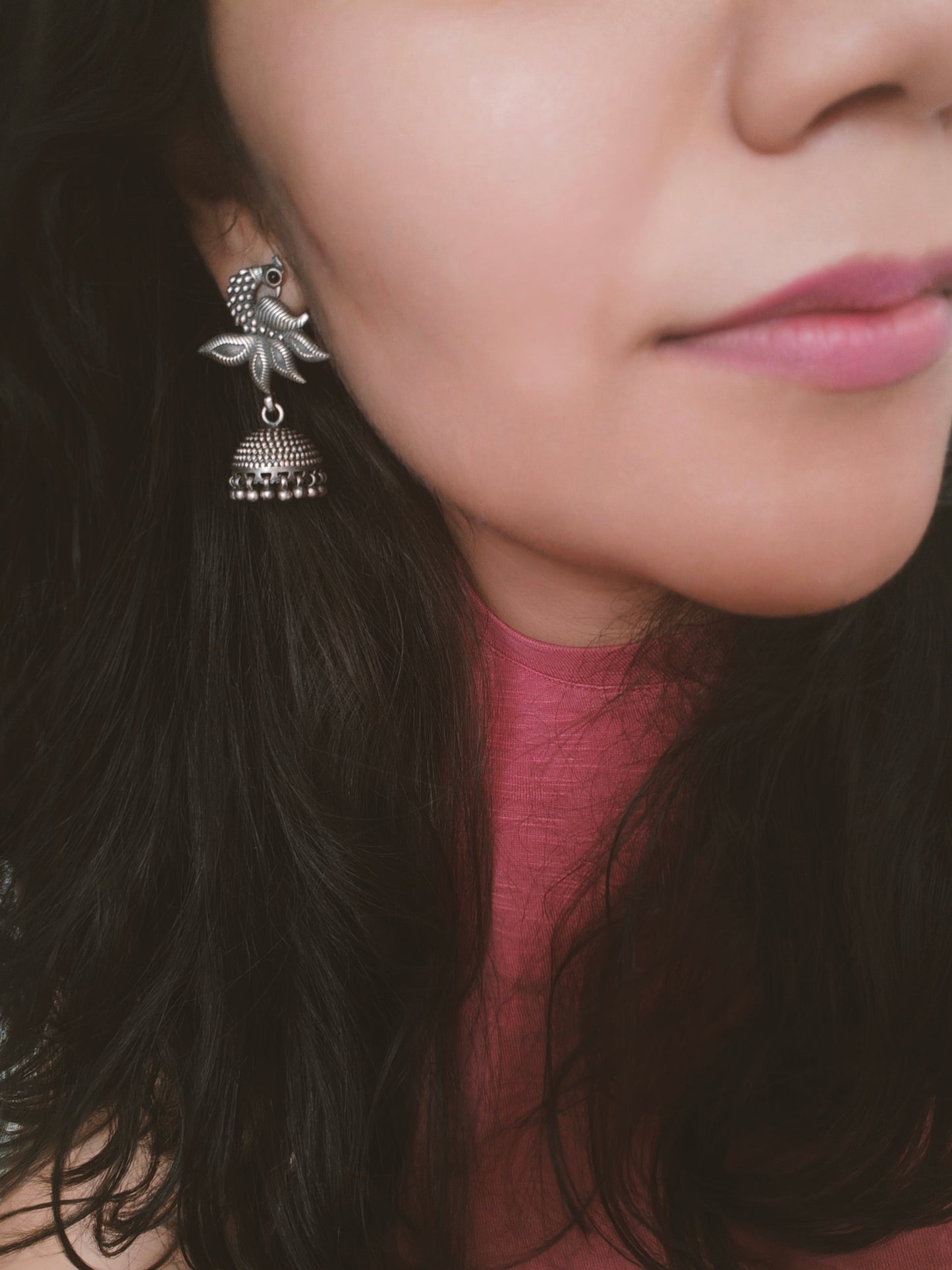 Silver jhumkis (earrings) on a peacock stud with open feather design and highlighted plumage