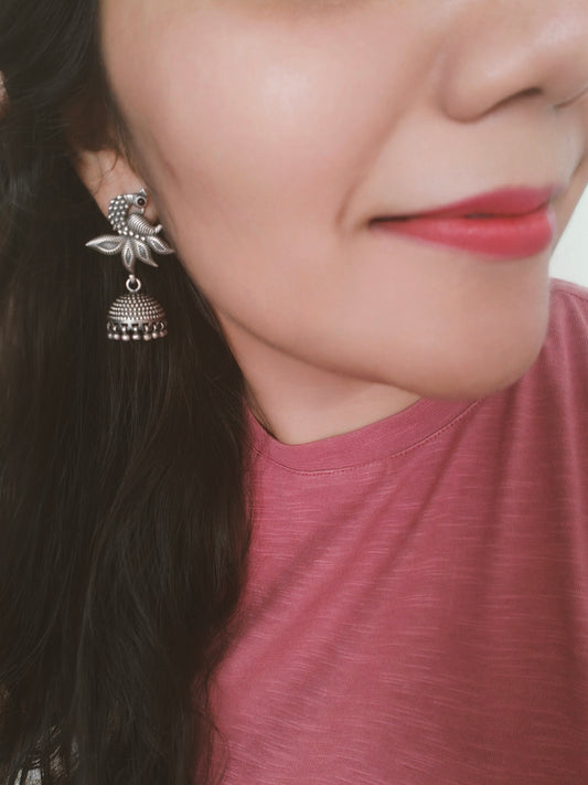 Silver jhumkis (earrings) on a peacock stud with open feather design and highlighted plumage