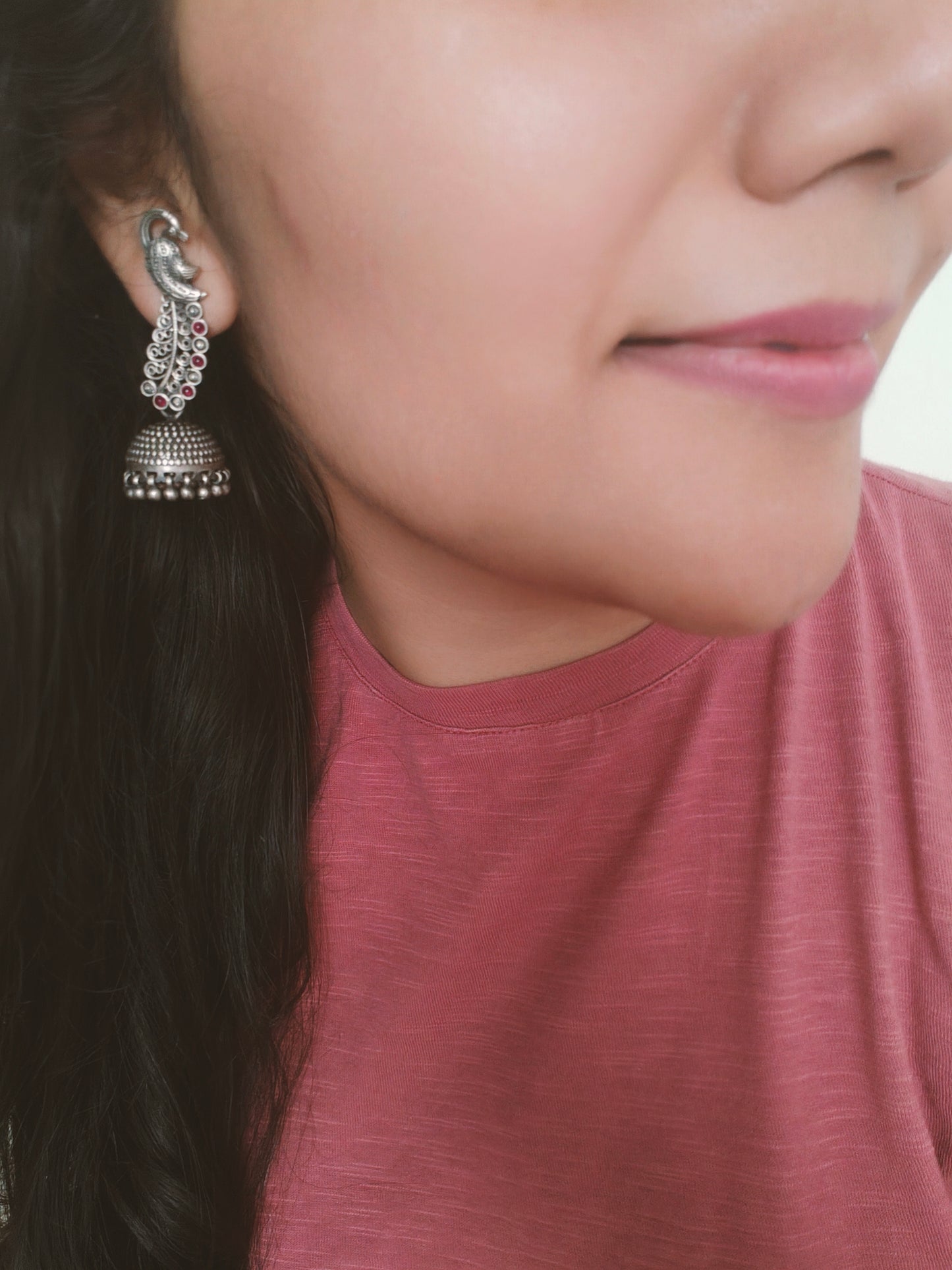 Silver jhumkis (earrings) on peacock studs with long carved feathers