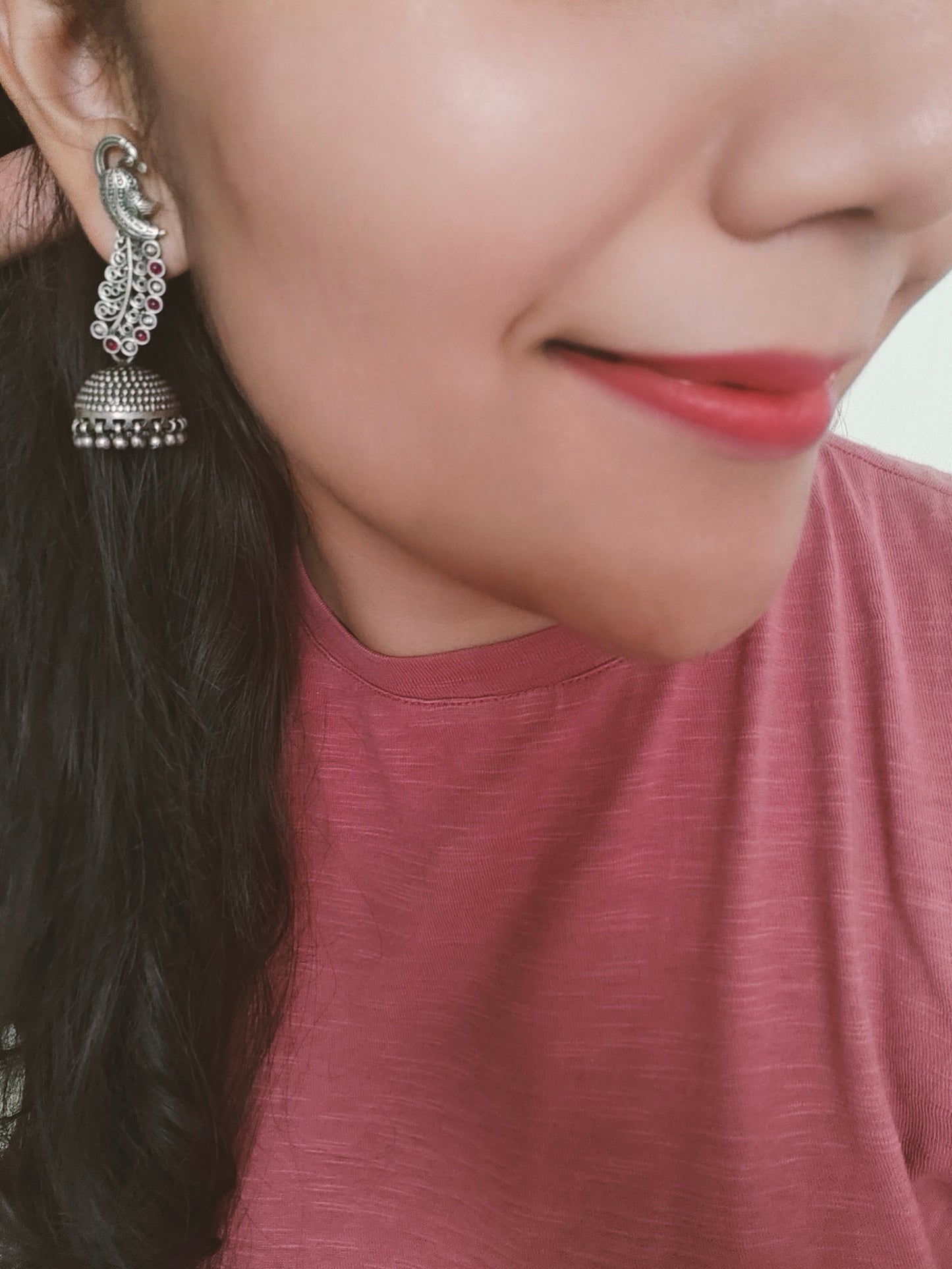 Silver jhumkis (earrings) on peacock studs with long carved feathers