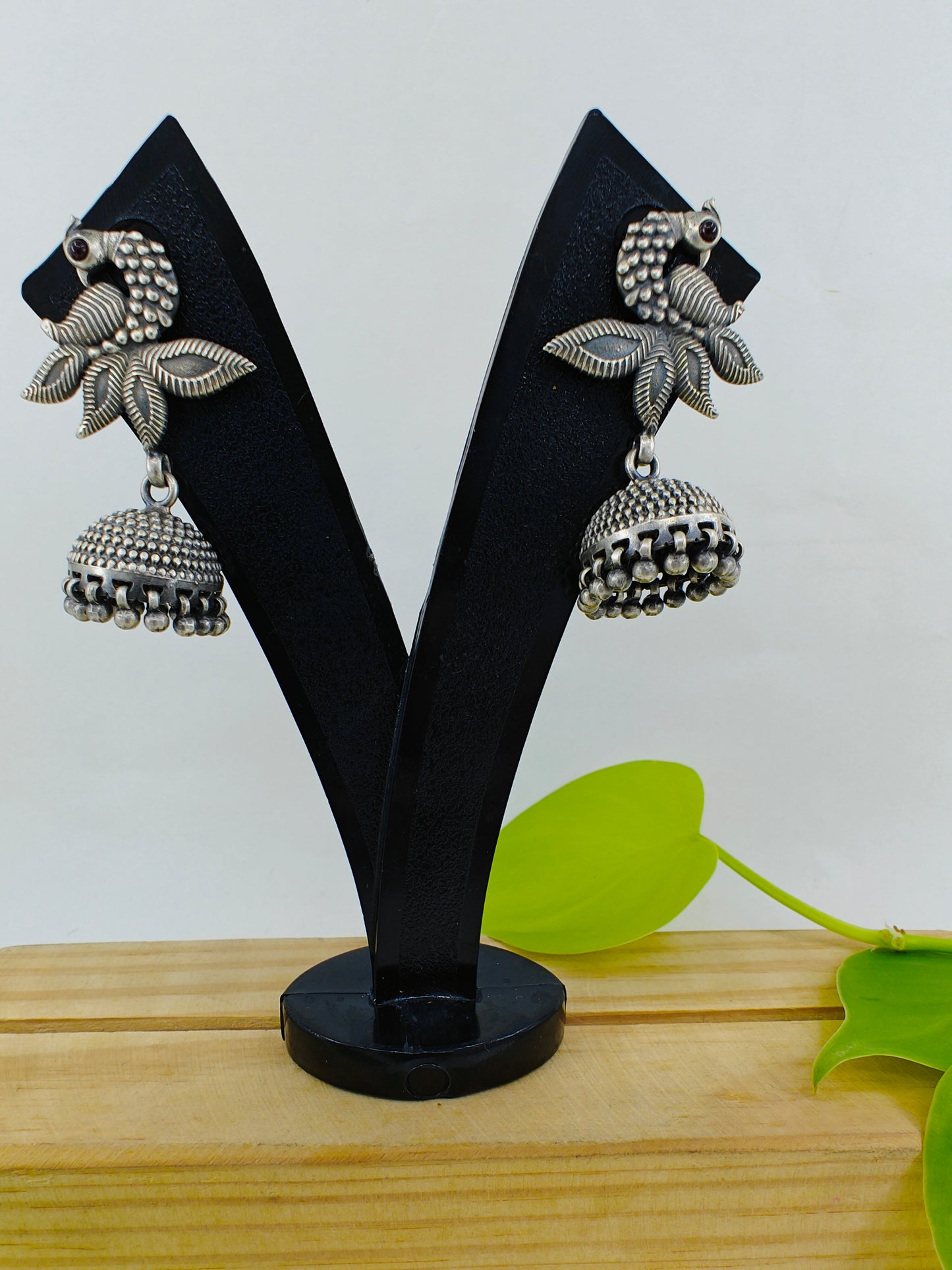 Silver jhumkis (earrings) on a peacock stud with open feather design and highlighted plumage