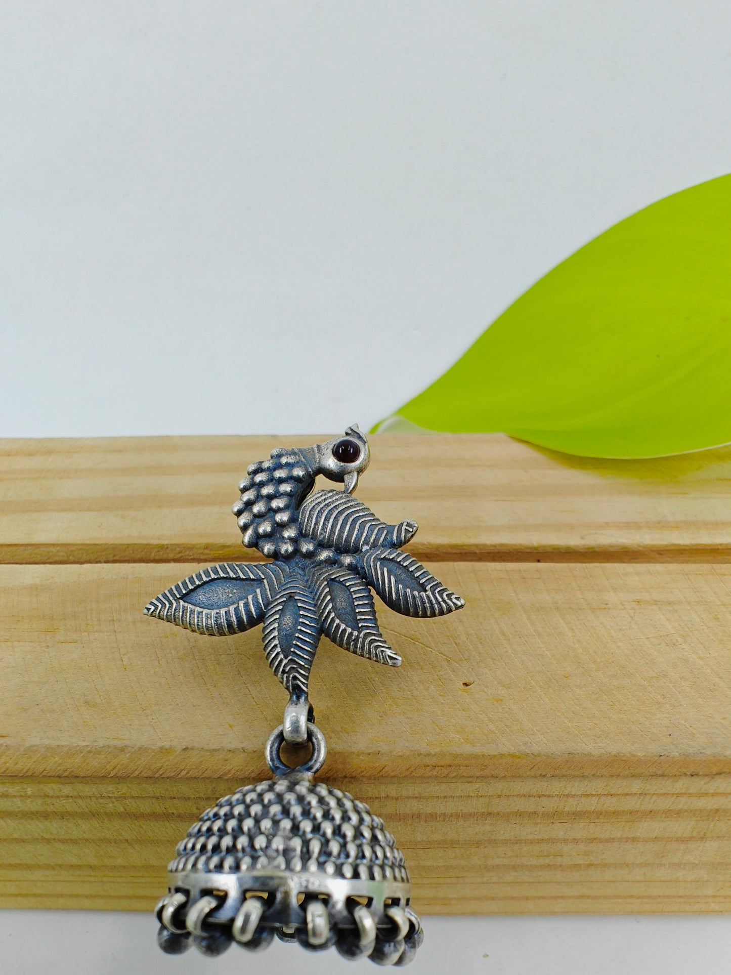 Silver jhumkis (earrings) on a peacock stud with open feather design and highlighted plumage