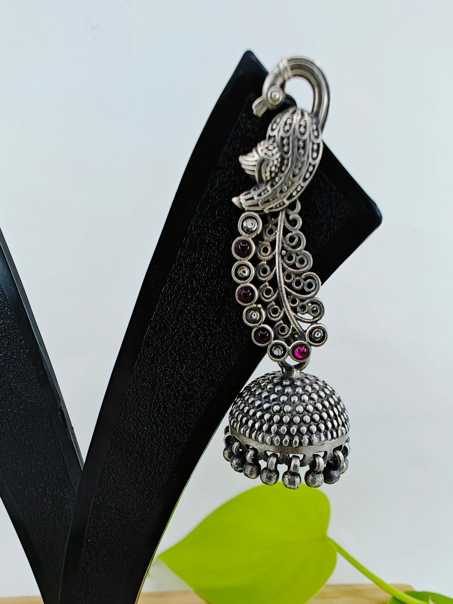 Silver jhumkis (earrings) on peacock studs with long carved feathers