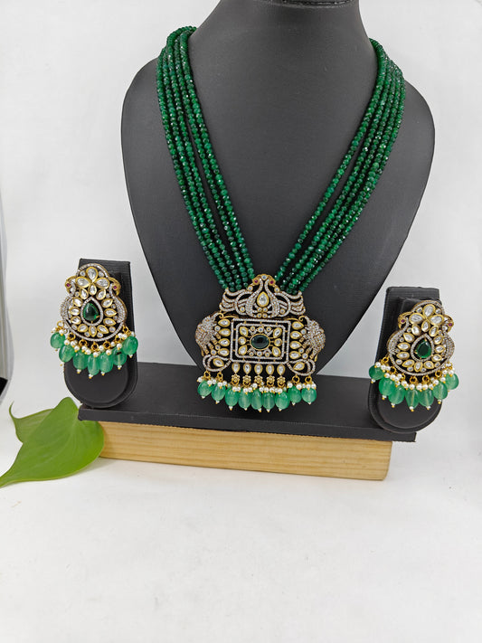 Set in antique gold finish with an elephant and peacock motif pendant in Kundan,CZ and emerald green stones on green strands