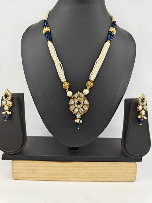 Set in gold finish with kundan, sapphire blue stone on tear drop shaped pendant on poth pearl string.