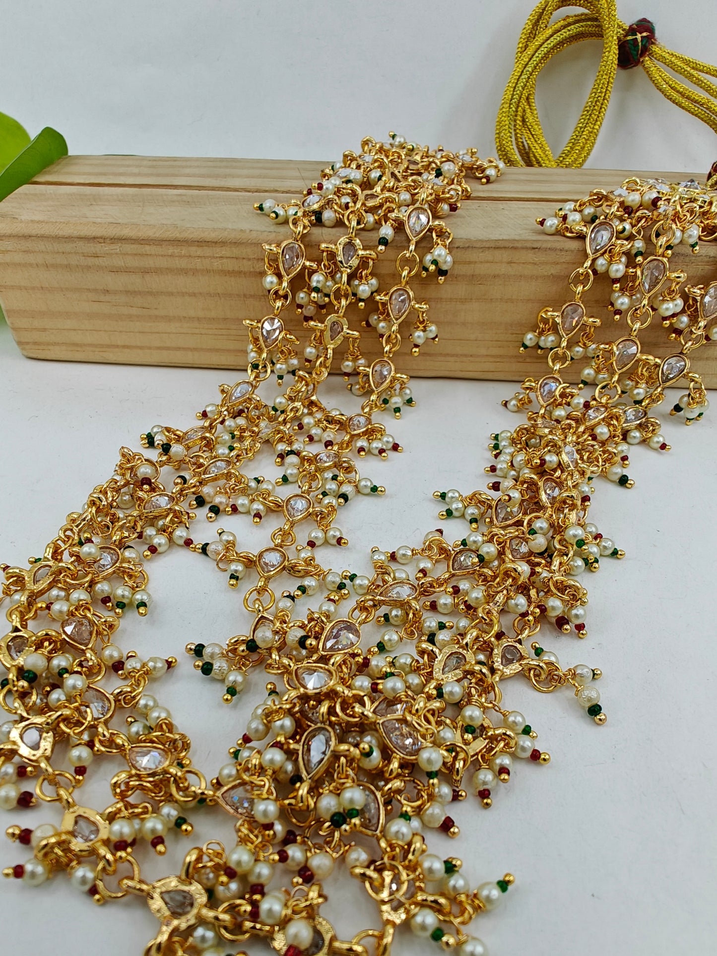 Set in gold finish with transparent stones,pearls and red green stones