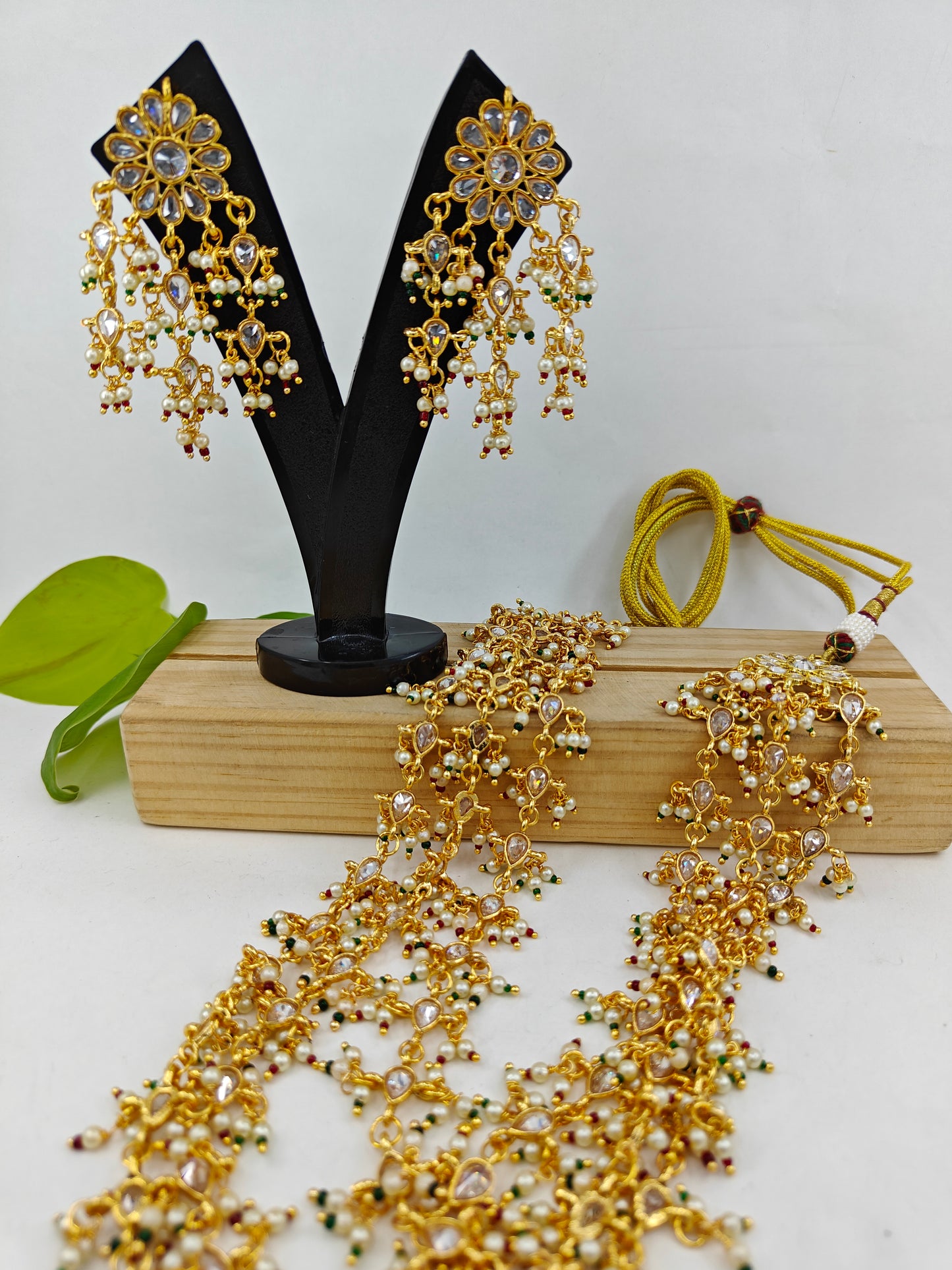 Set in gold finish with transparent stones,pearls and red green stones