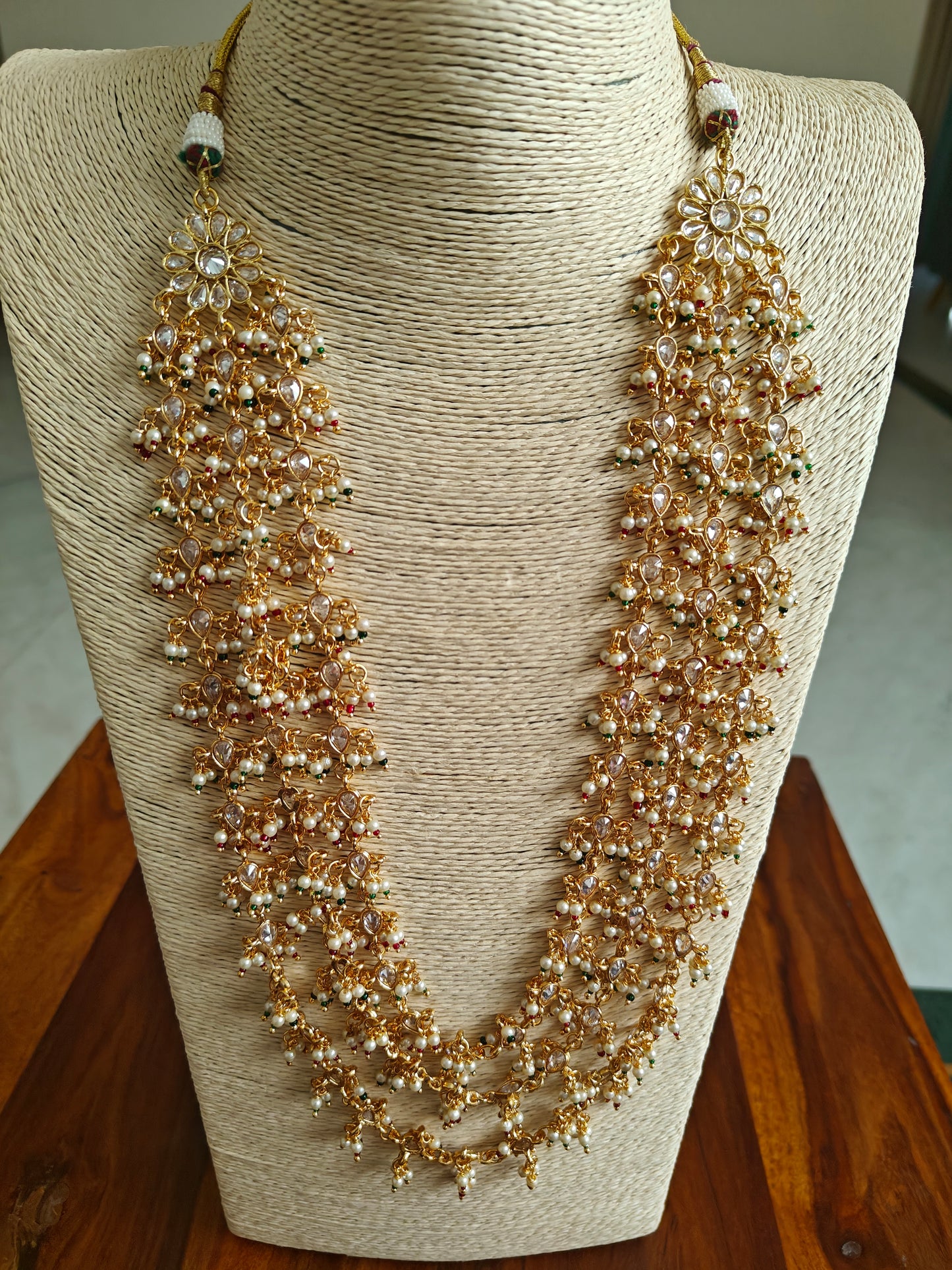 Set in gold finish with transparent stones,pearls and red green stones