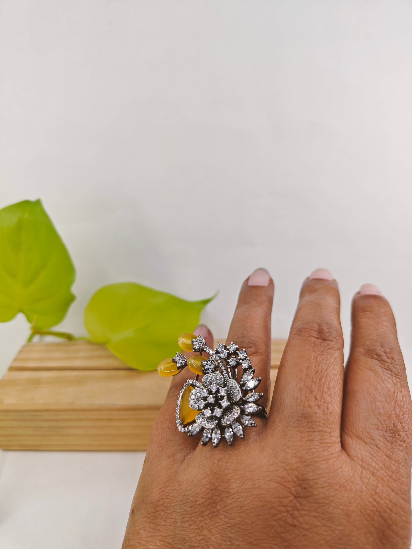 Ring in antique platinum finish with a flower spray design with topaz colour stones