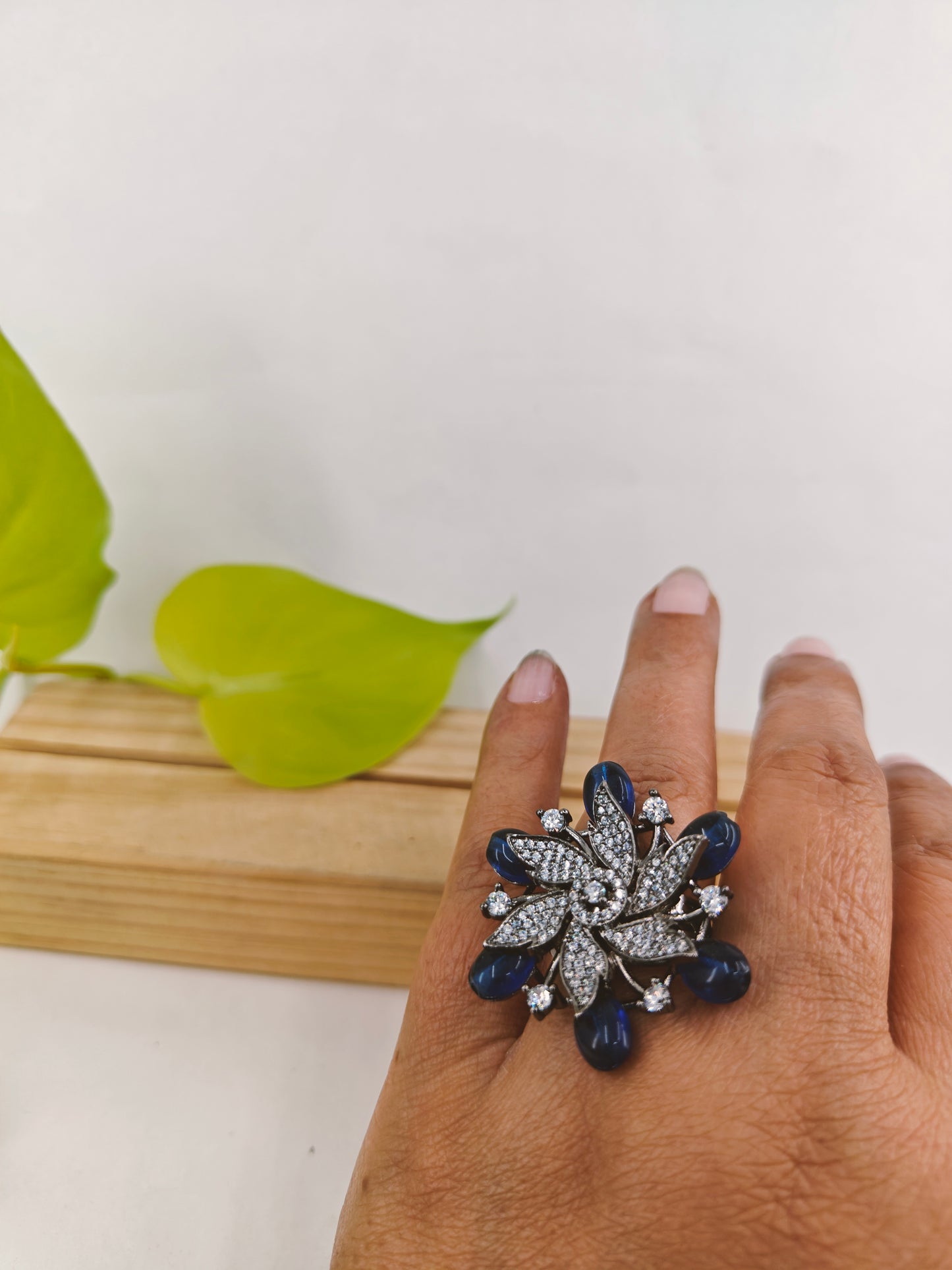 Antique platinum finish ring in a flower motif with sapphire stones highlighted with CZ