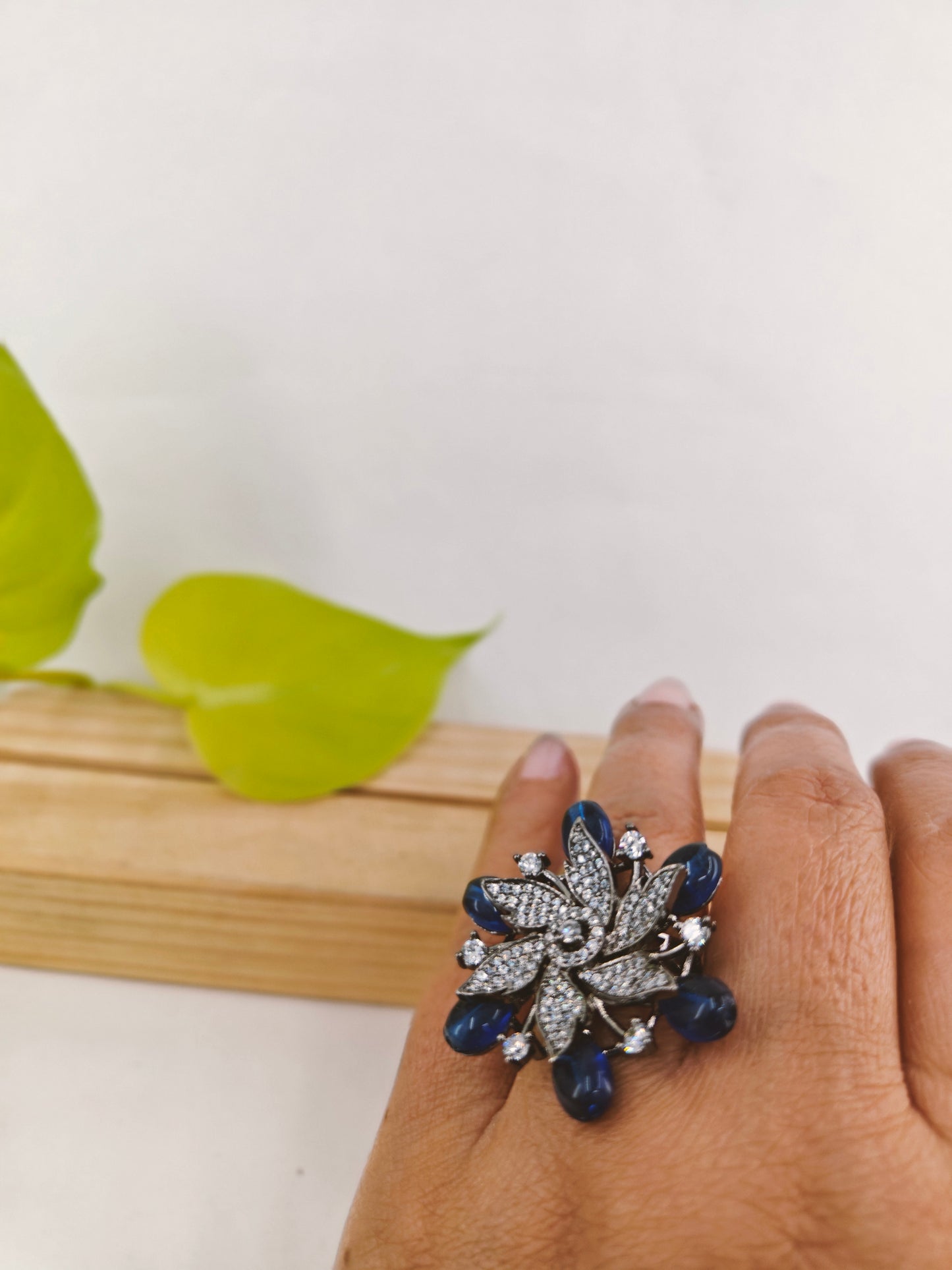 Antique platinum finish ring in a flower motif with sapphire stones highlighted with CZ