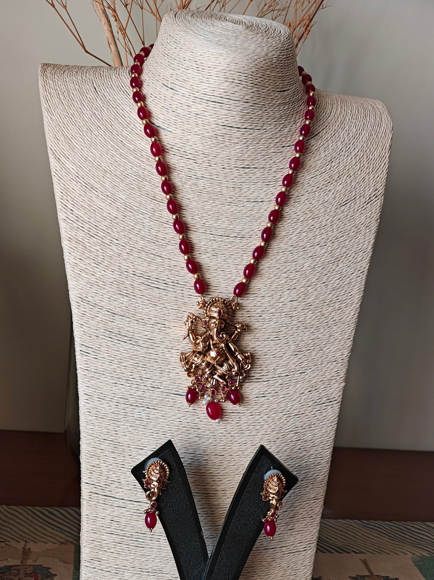 Gold finish Temple set ,carved Ganesha with red stone highlights on red bead necklace.