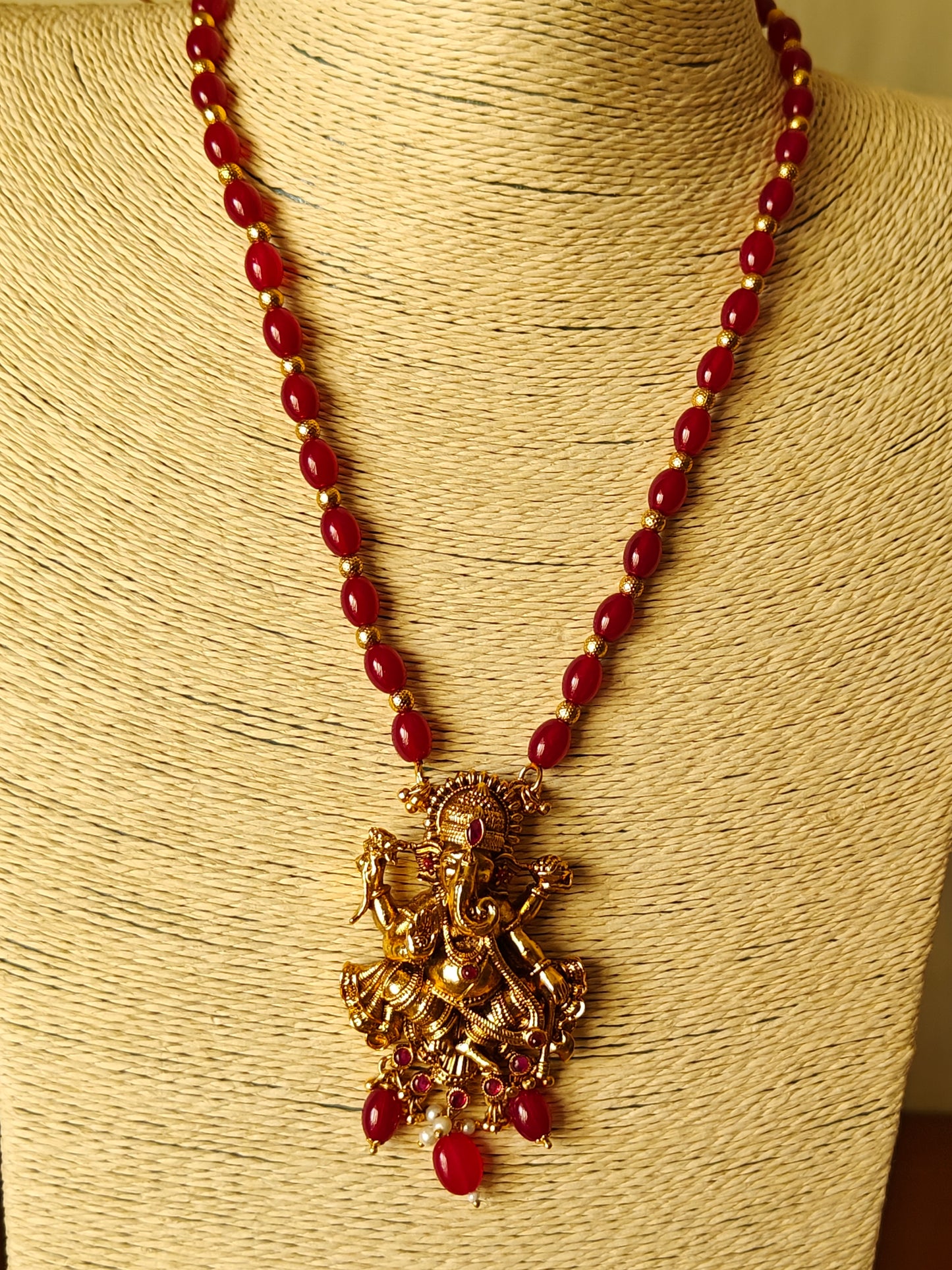 Gold finish Temple set ,carved Ganesha with red stone highlights on red bead necklace.