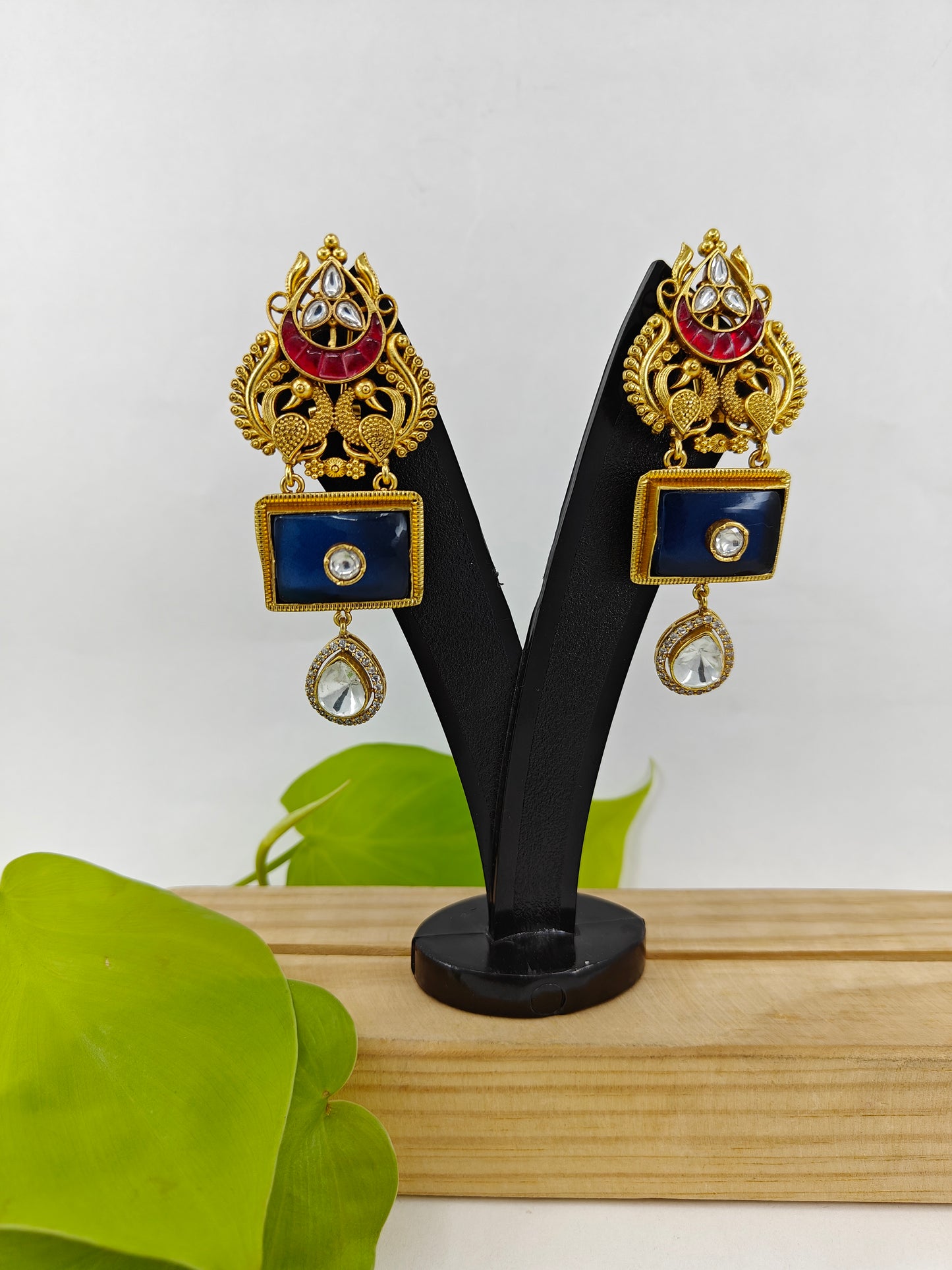 Golden earrings with two peacock motif and black and red stone highlighted with kundan