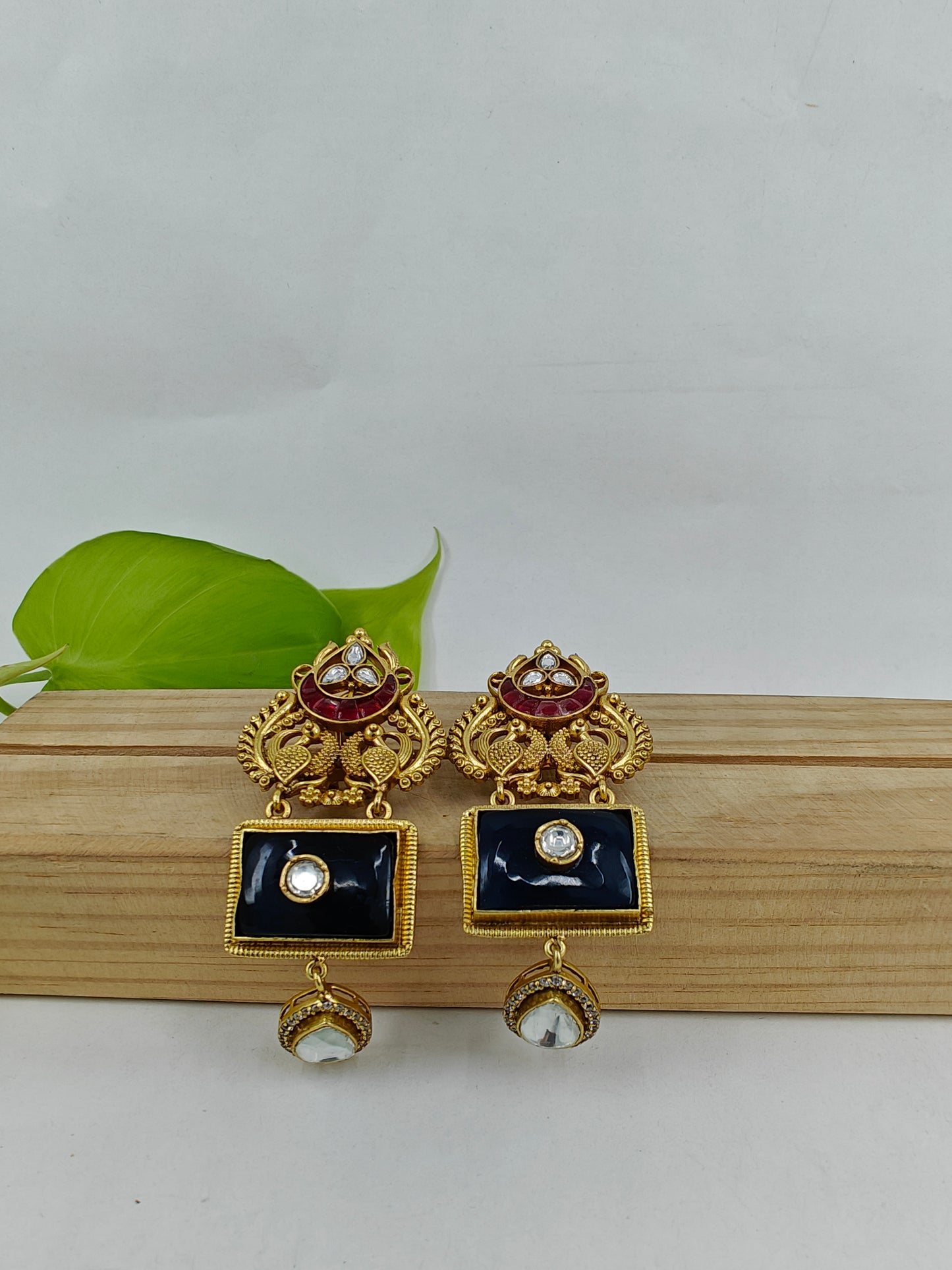 Golden earrings with two peacock motif and black and red stone highlighted with kundan