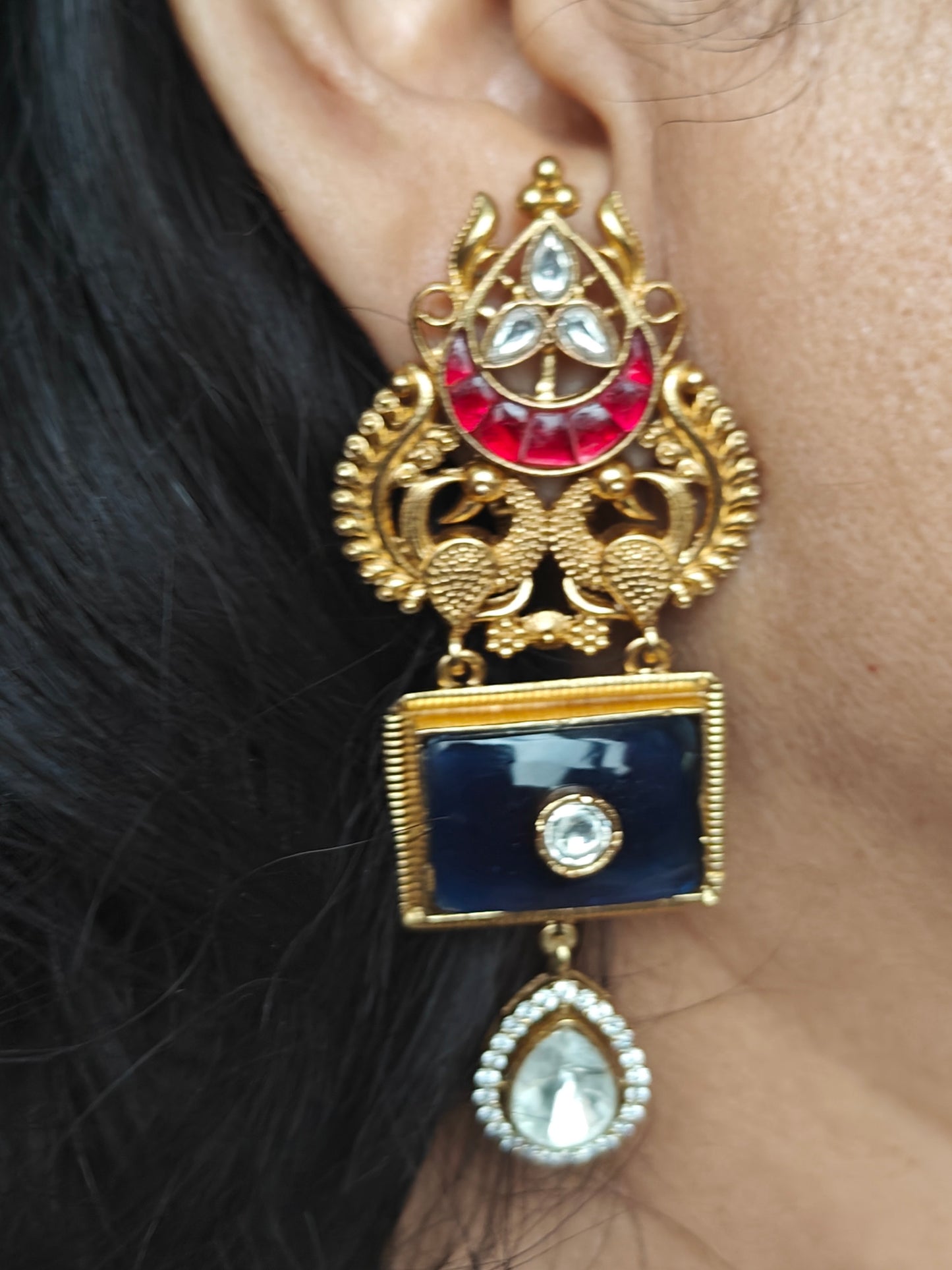 Golden earrings with two peacock motif and black and red stone highlighted with kundan