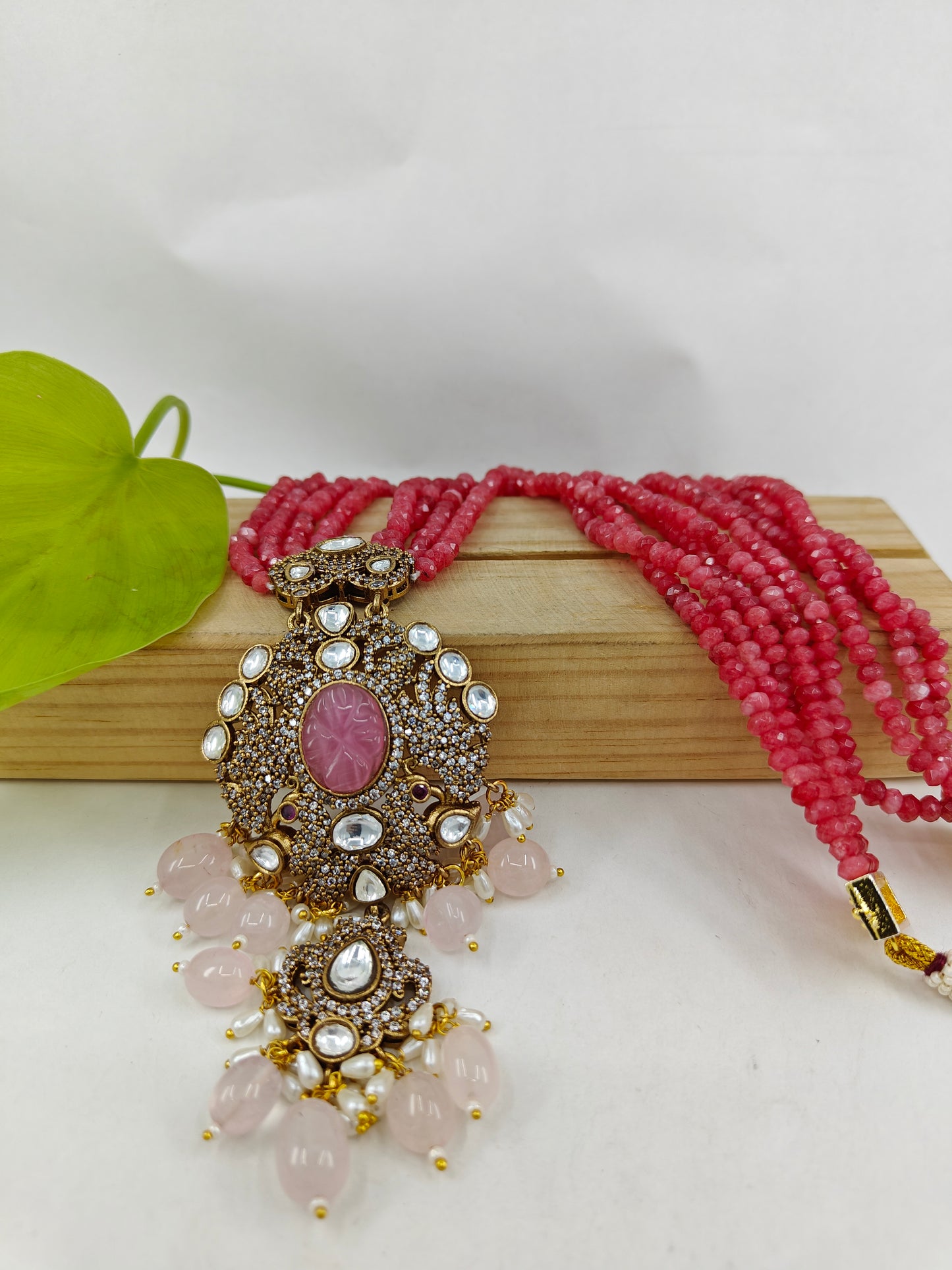 Set in gajari/ peach stone strings with a peacock  motif pendant