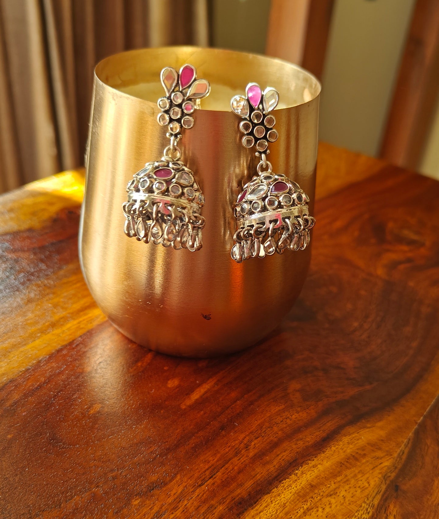 Silver jhumkis (earrings) with red and transparent stone inlay