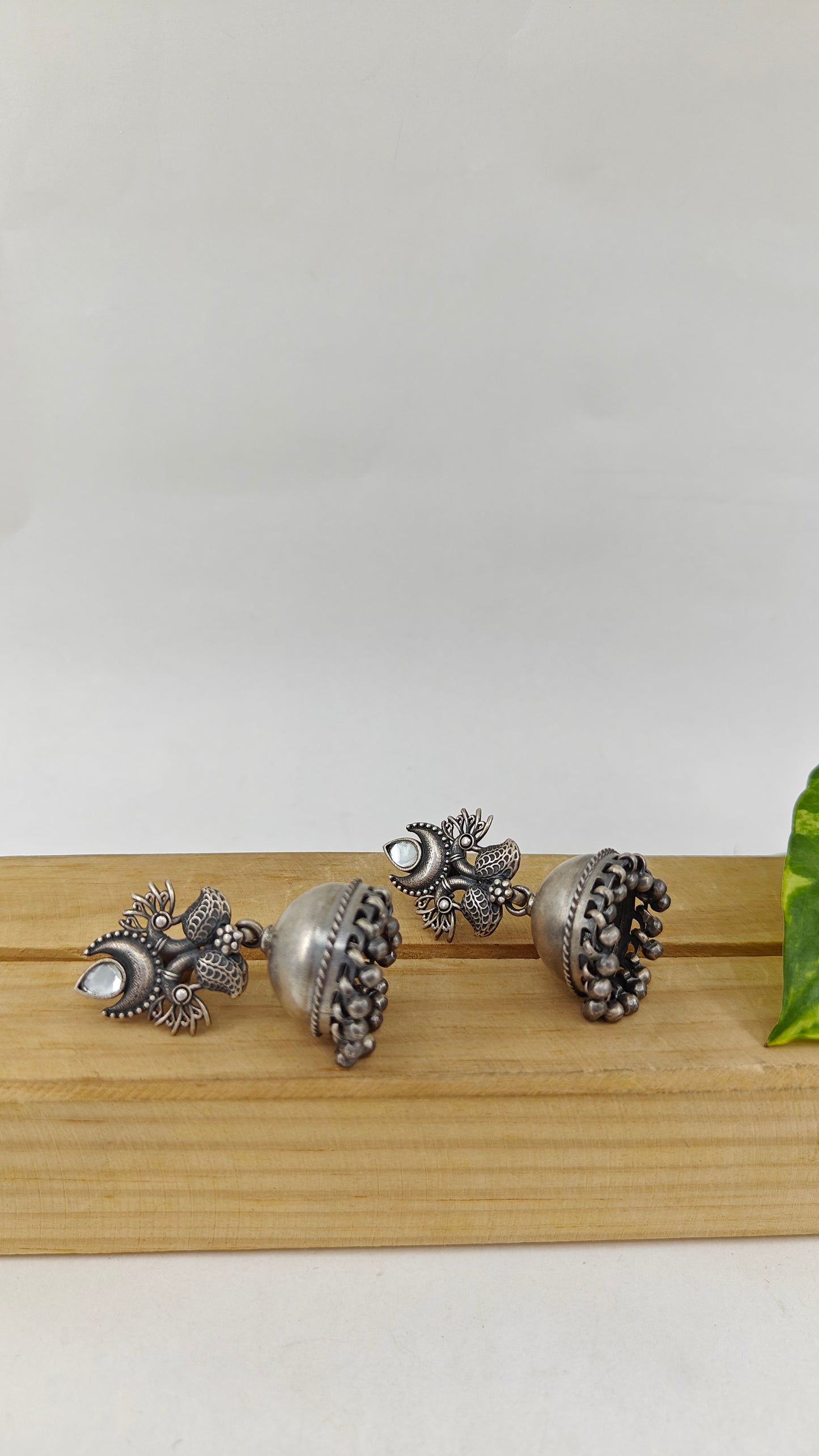 Silver jhumkis (earrings) on peacock and white stone stud