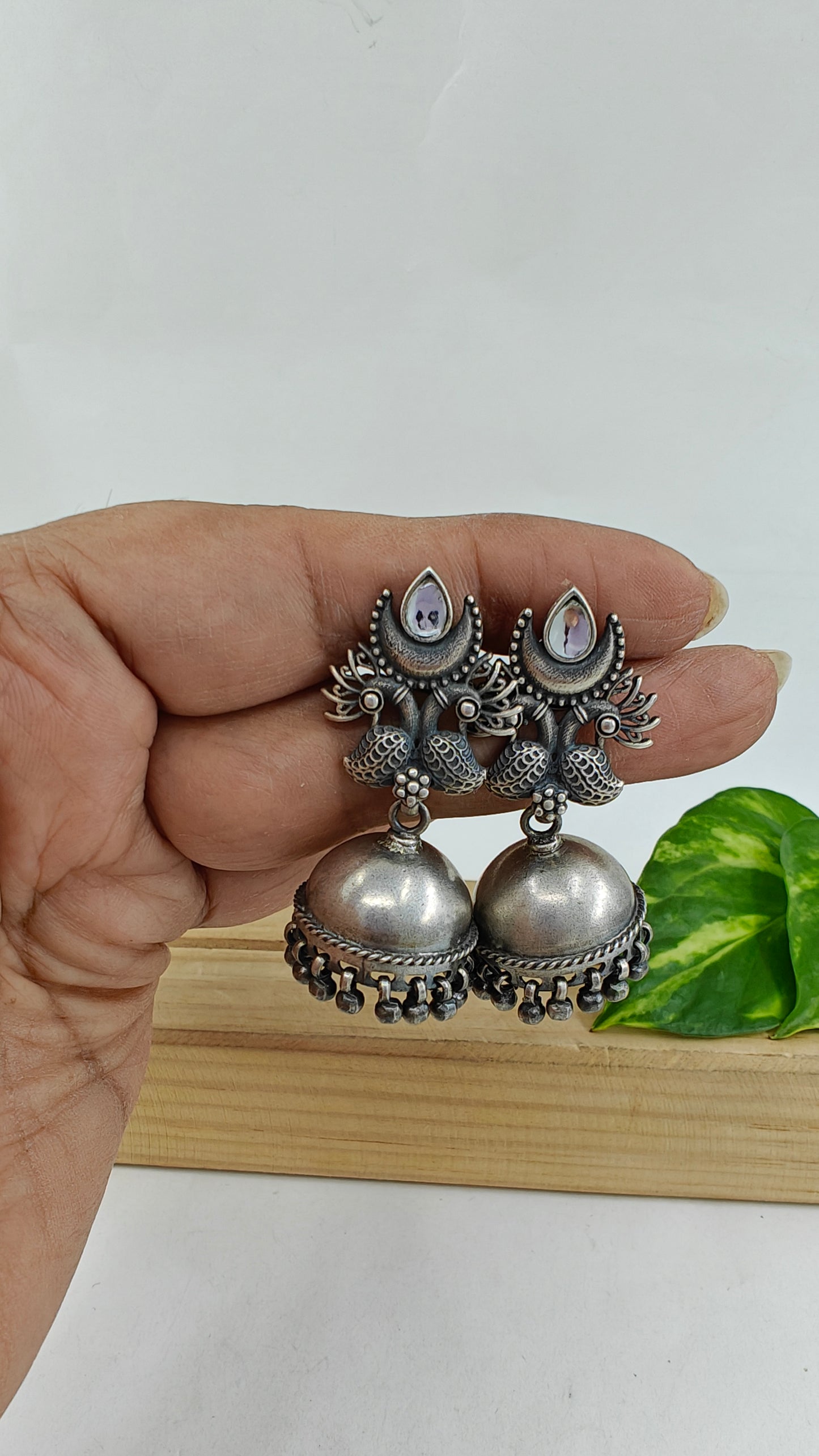 Silver jhumkis (earrings) on peacock and white stone stud