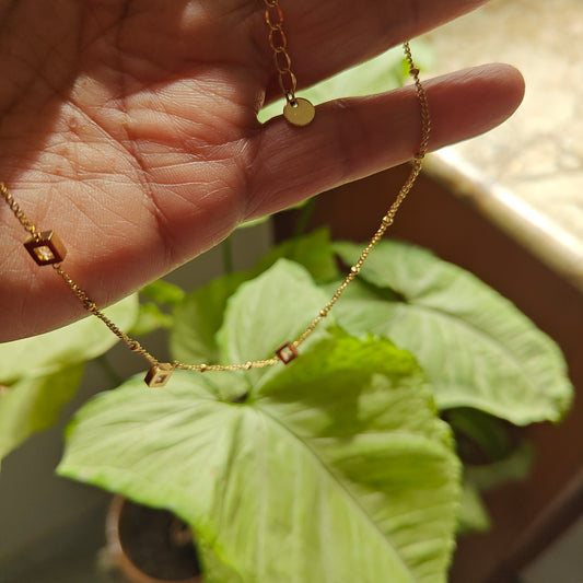 Gold chain with suspended square pieces with stones