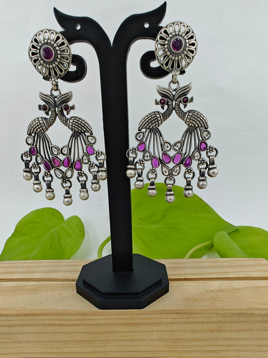 Silver earrings having 2 peacock motif with pink/green and clear stones on a round stud