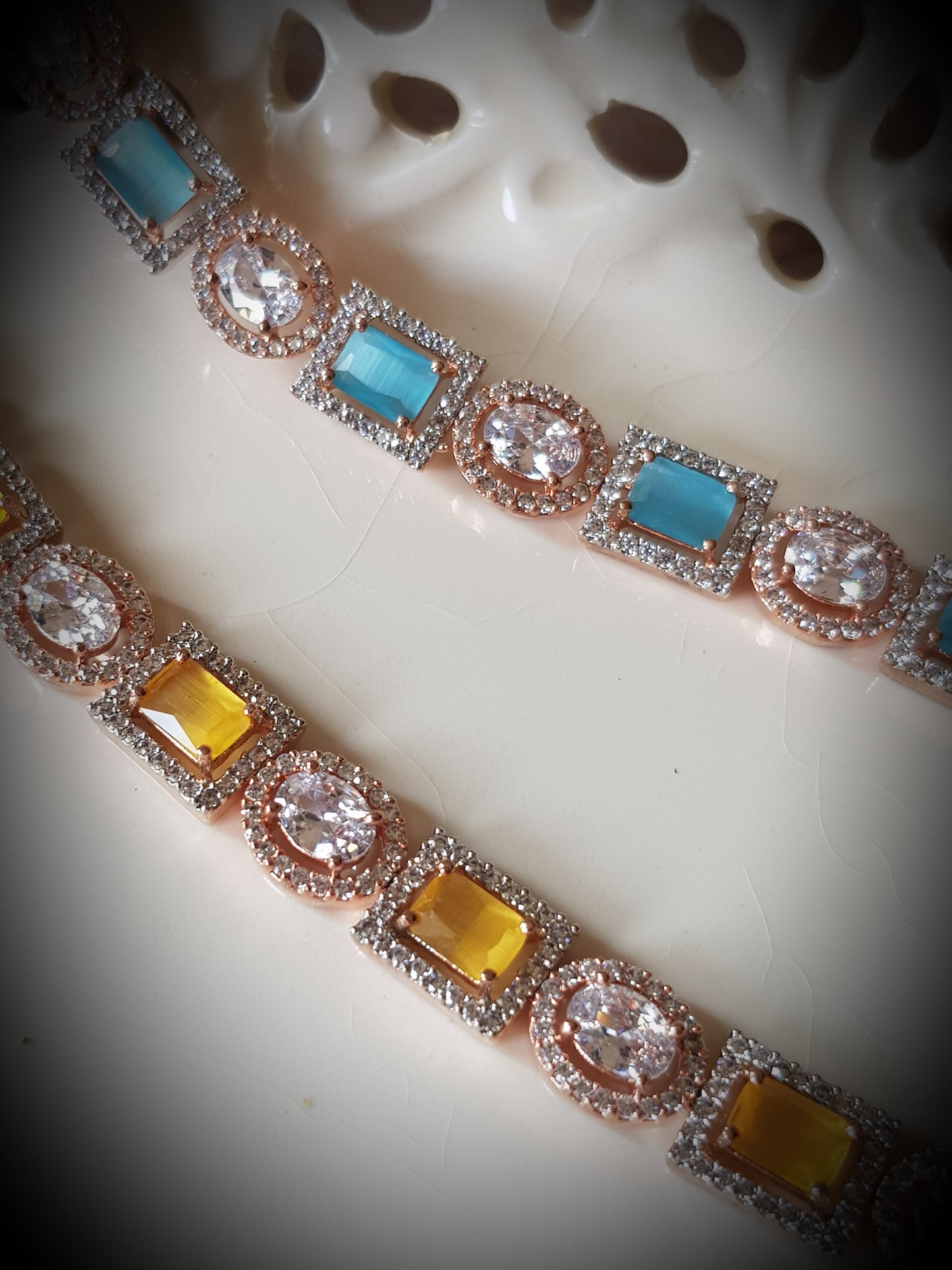 Platinum finish bracelet, square aqua/topaz stone surrounded by CZ interspaced with oval clear stone with CZ around