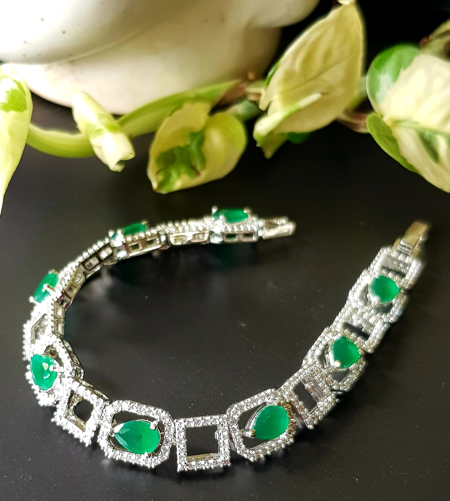 Platinum finish bracelet with teardrop emeralds framed with CZ