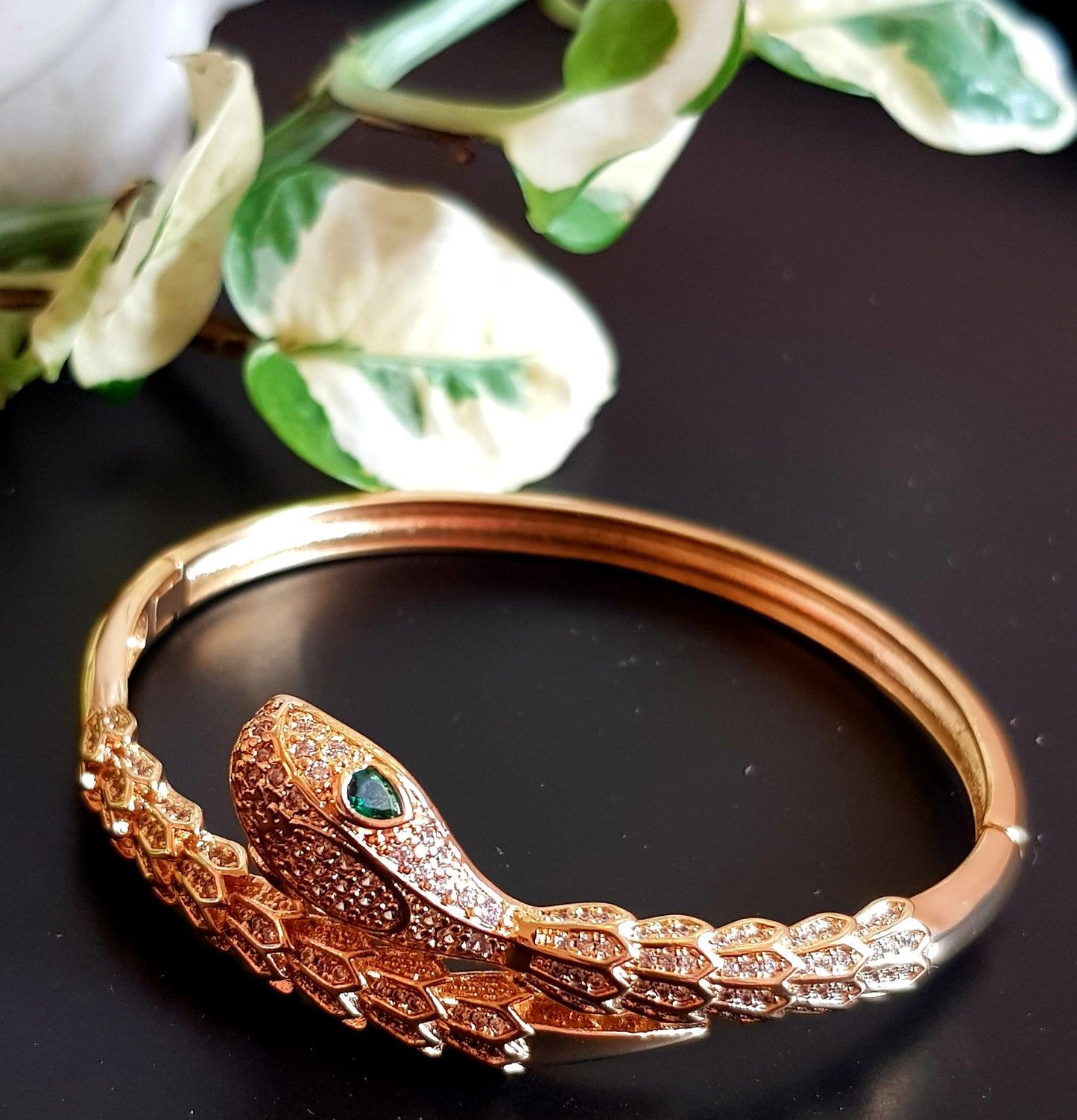 Snake shaped gold finish bracelet with emerald stone eye, embellished with CZ