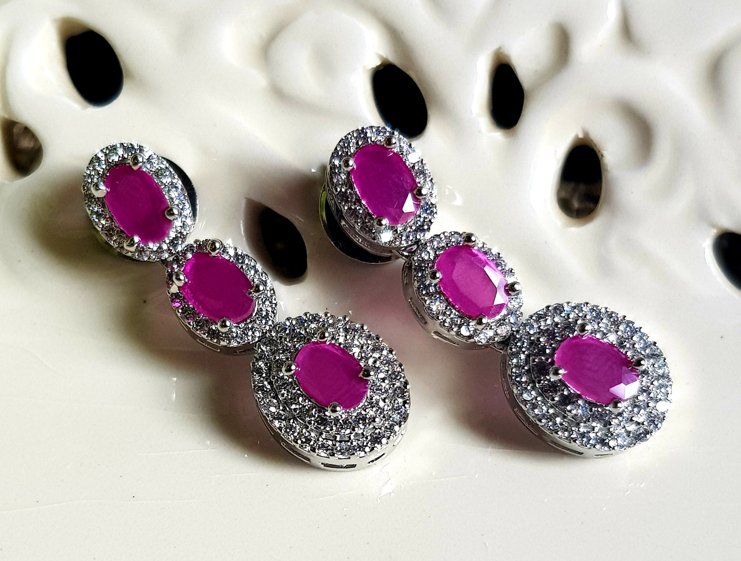 Platinum finish set in oval shaped ruby stone surrounded by CZ and matching pendant, matching earrings