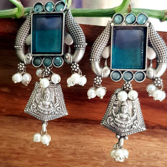 Antique silver finish earrings, peacock and Lakshmi motif around dual shaded square stone and pearl beads