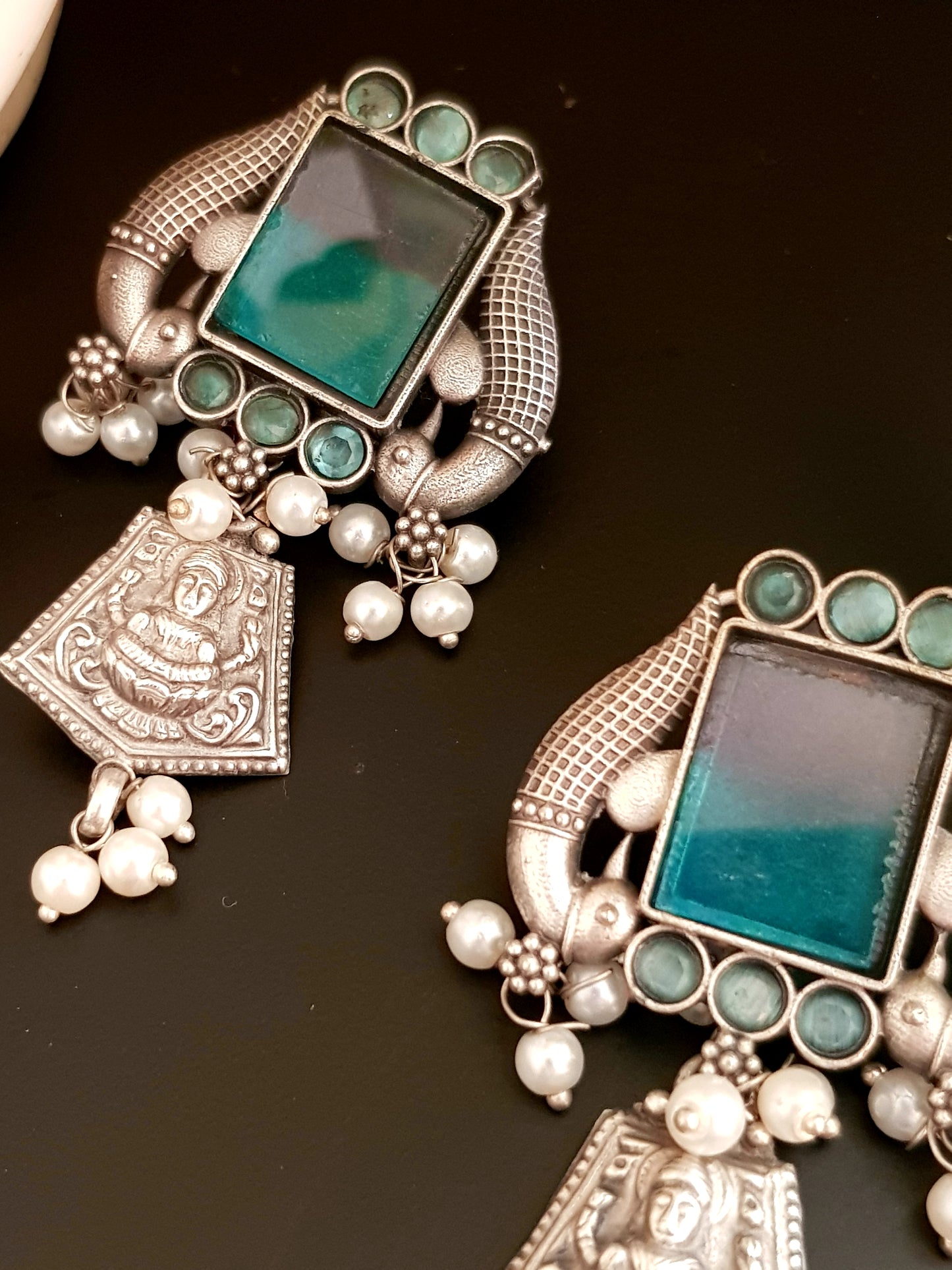 Antique silver finish earrings, peacock and Lakshmi motif around dual shaded square stone and pearl beads