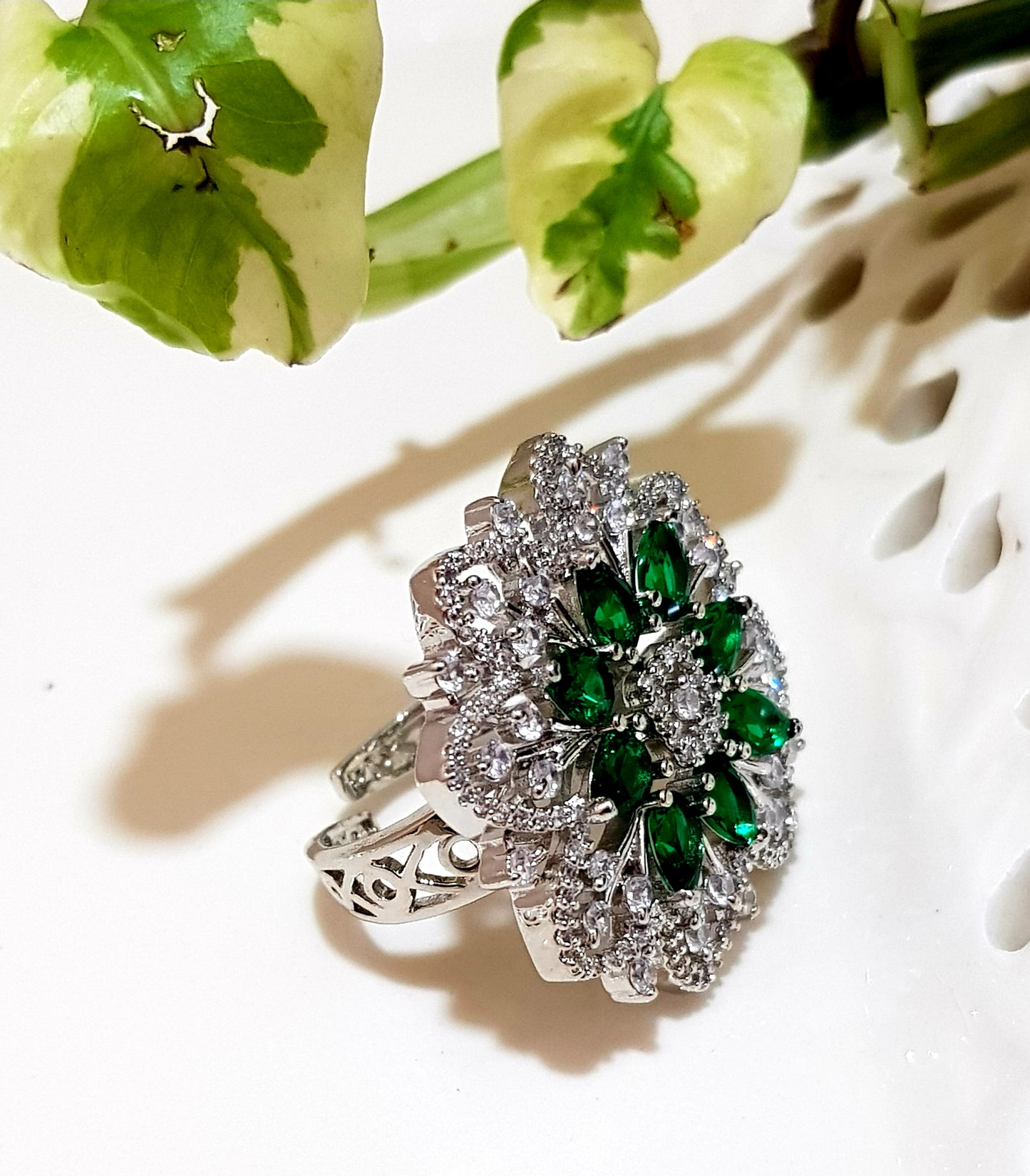 Platinum finish ring with emerald flower and CZ detailing all over