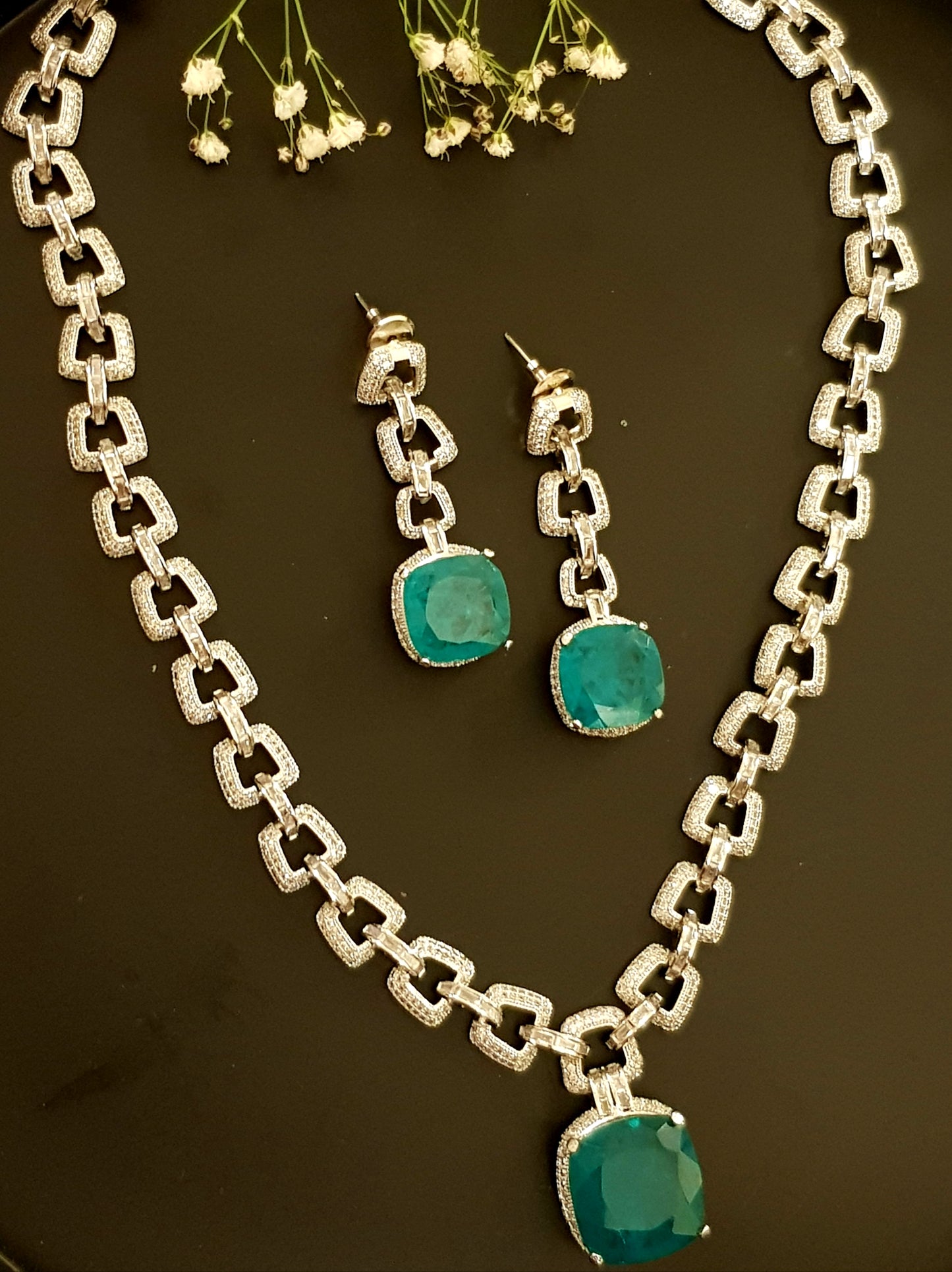 Platinum finish set, necklace in thick chain design with chunky emerald pendant, matching earrings