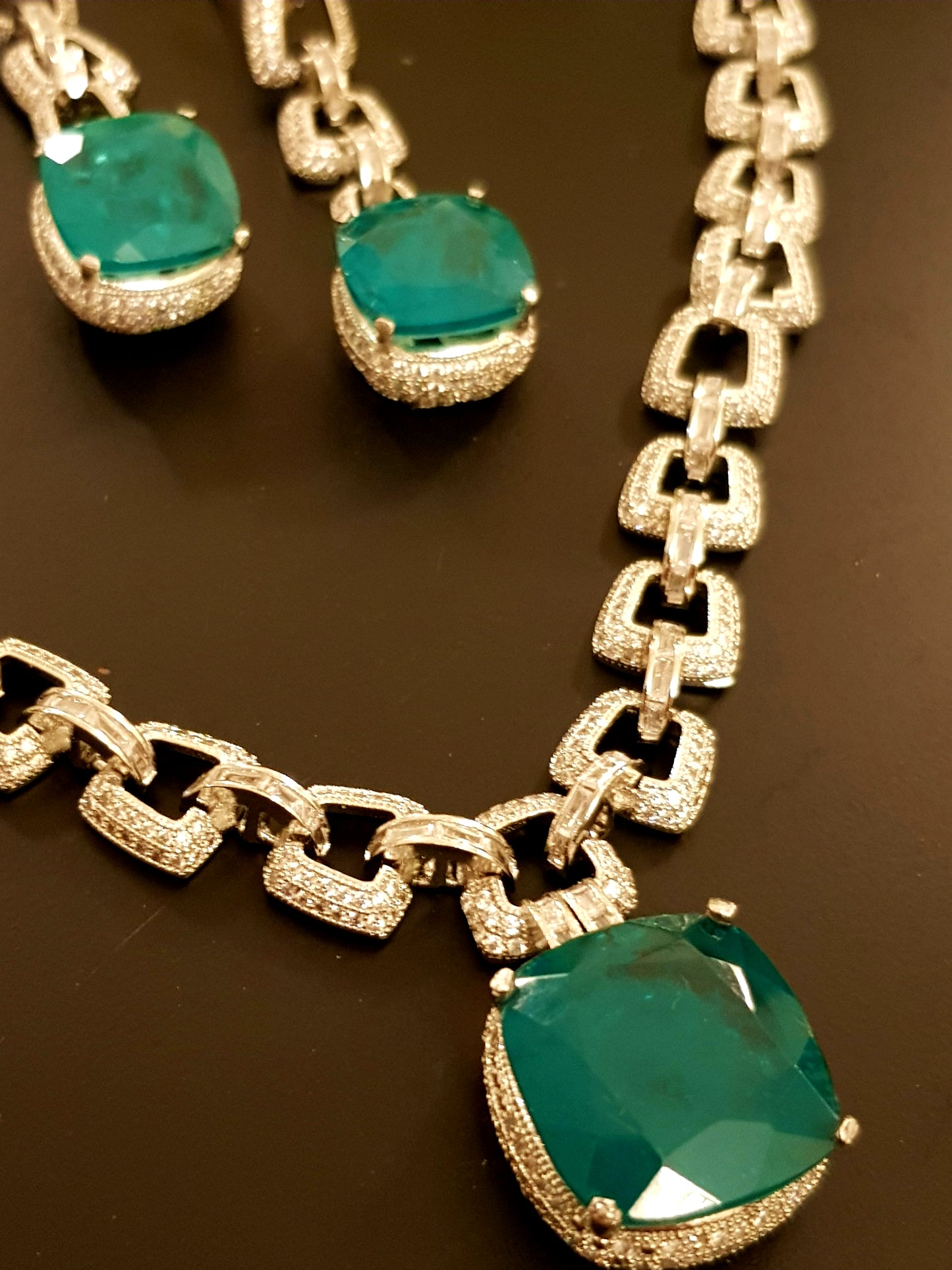 Platinum finish set, necklace in thick chain design with chunky emerald pendant, matching earrings