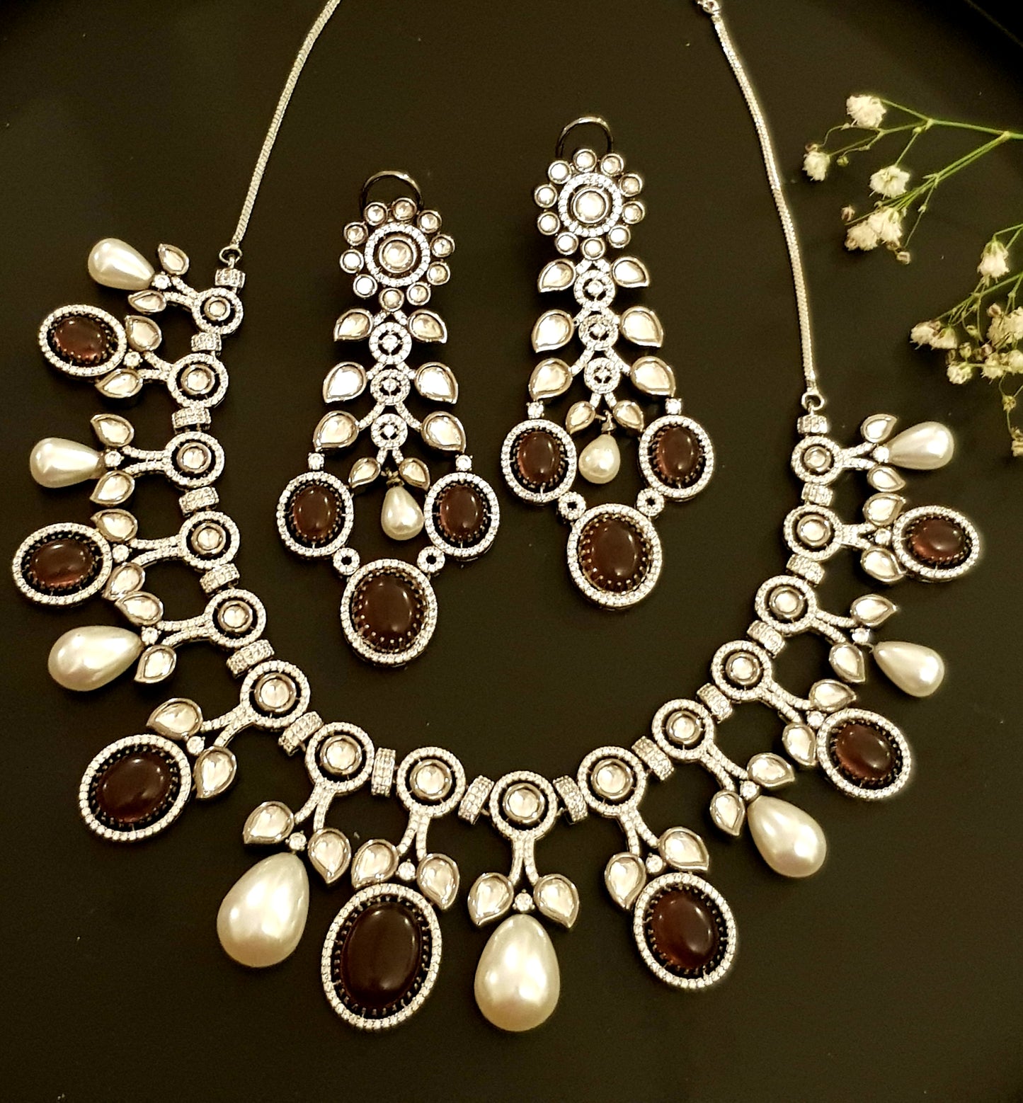 Platinum finish set with plum coloured stone, kundan, pearl and CZ necklace, matching earrings