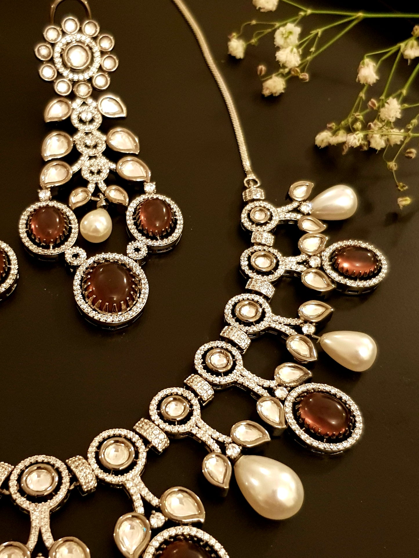 Platinum finish set with plum coloured stone, kundan, pearl and CZ necklace, matching earrings