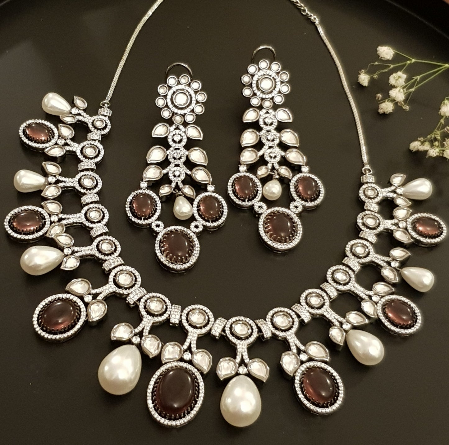 Platinum finish set with plum coloured stone, kundan, pearl and CZ necklace, matching earrings