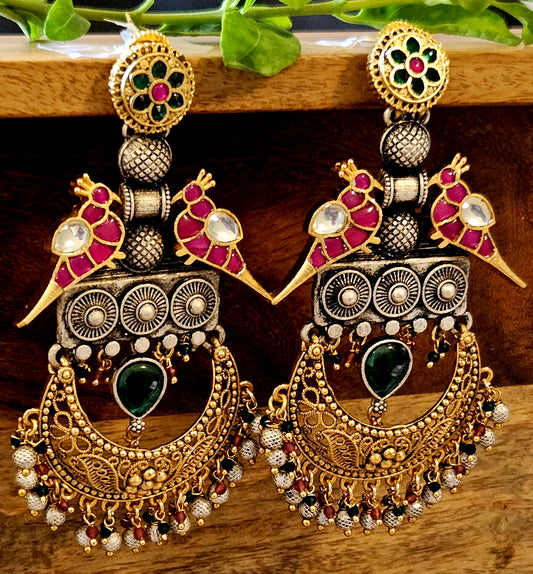 Dual tone long earrings, two red kemp stone parrots with crescent hanging piece, kundan and red-green stone detailing