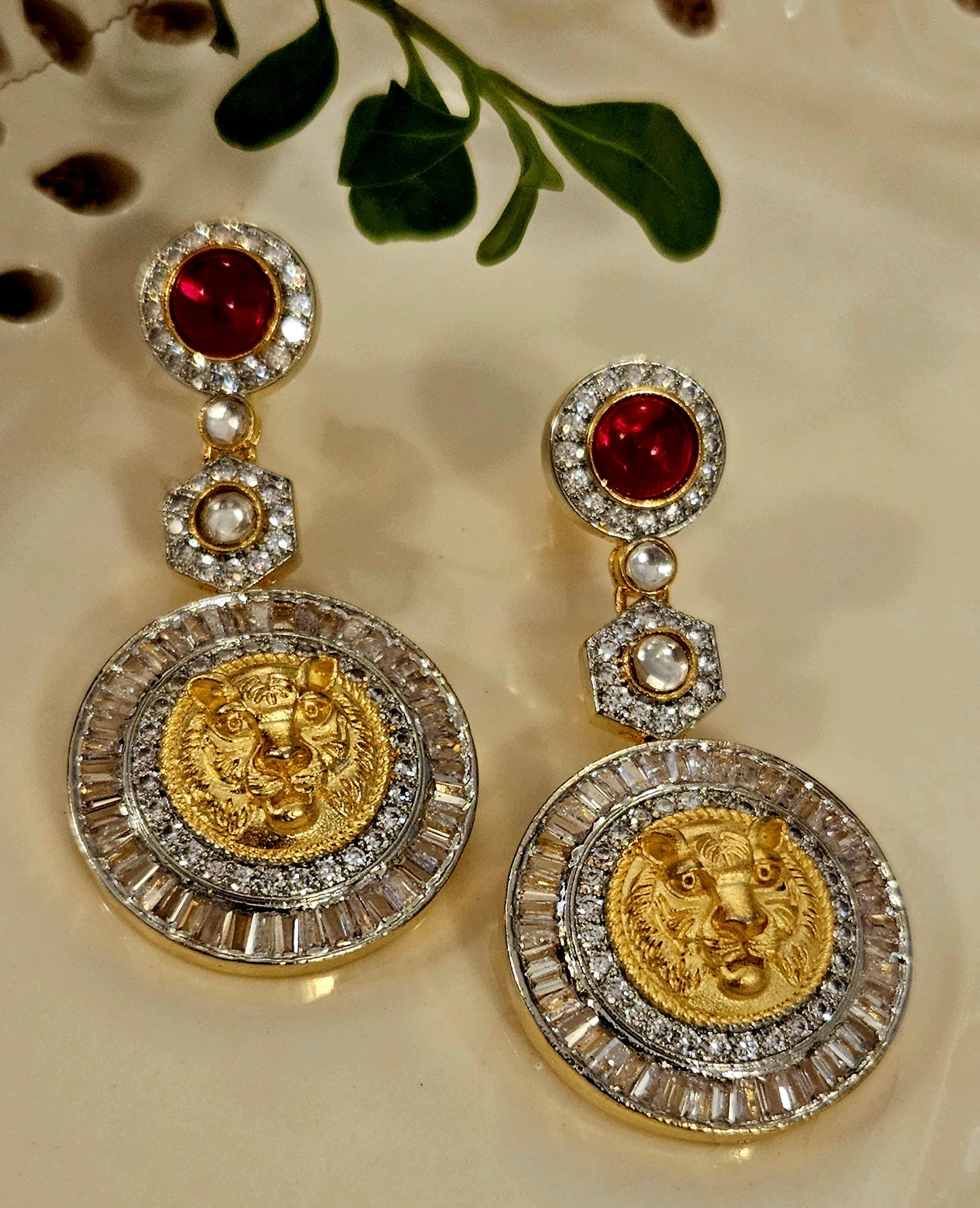 Platinum finish long earrings with lion face surrounded by clear stone hanging under pink/red stone stud