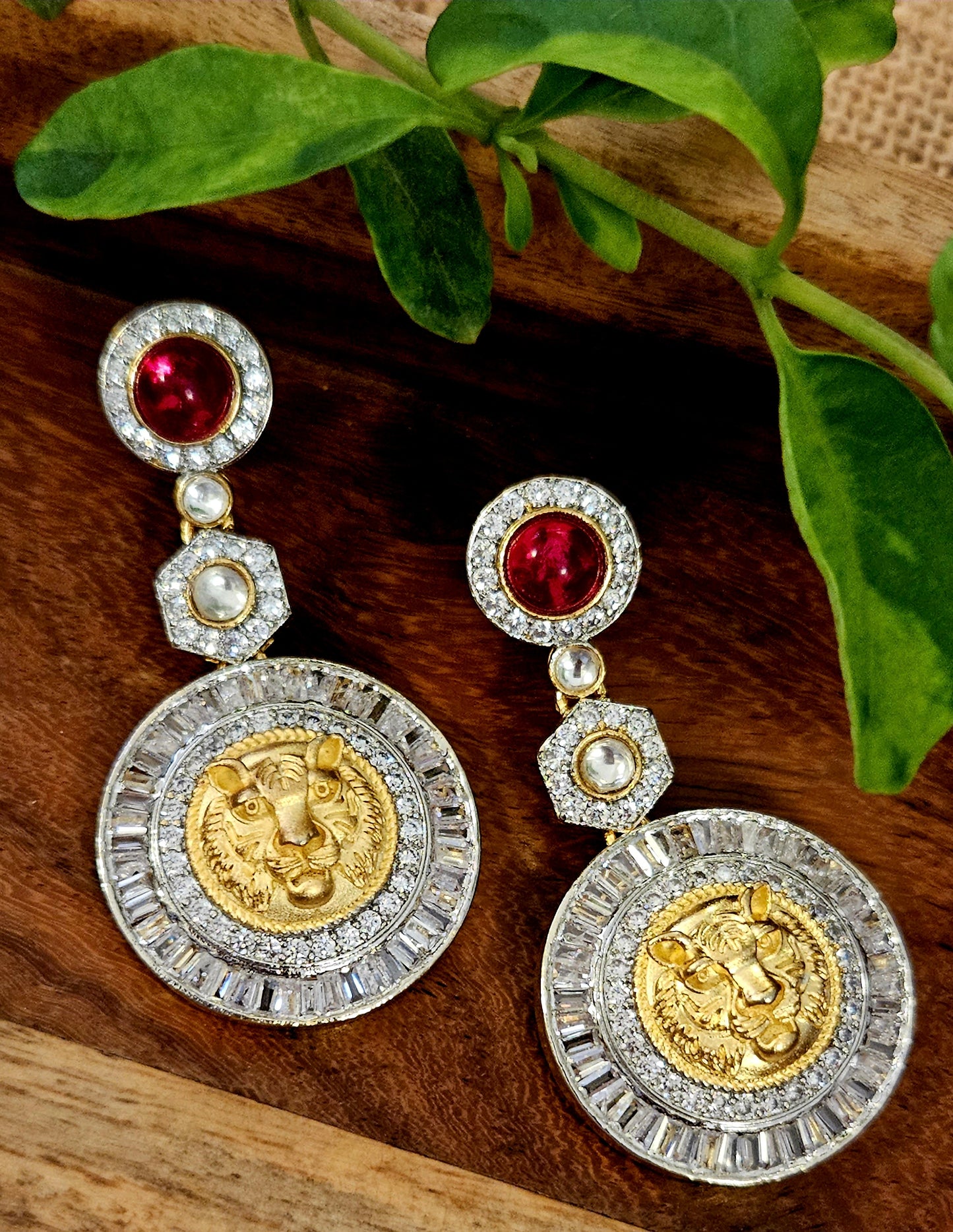 Platinum finish long earrings with lion face surrounded by clear stone hanging under pink/red stone stud