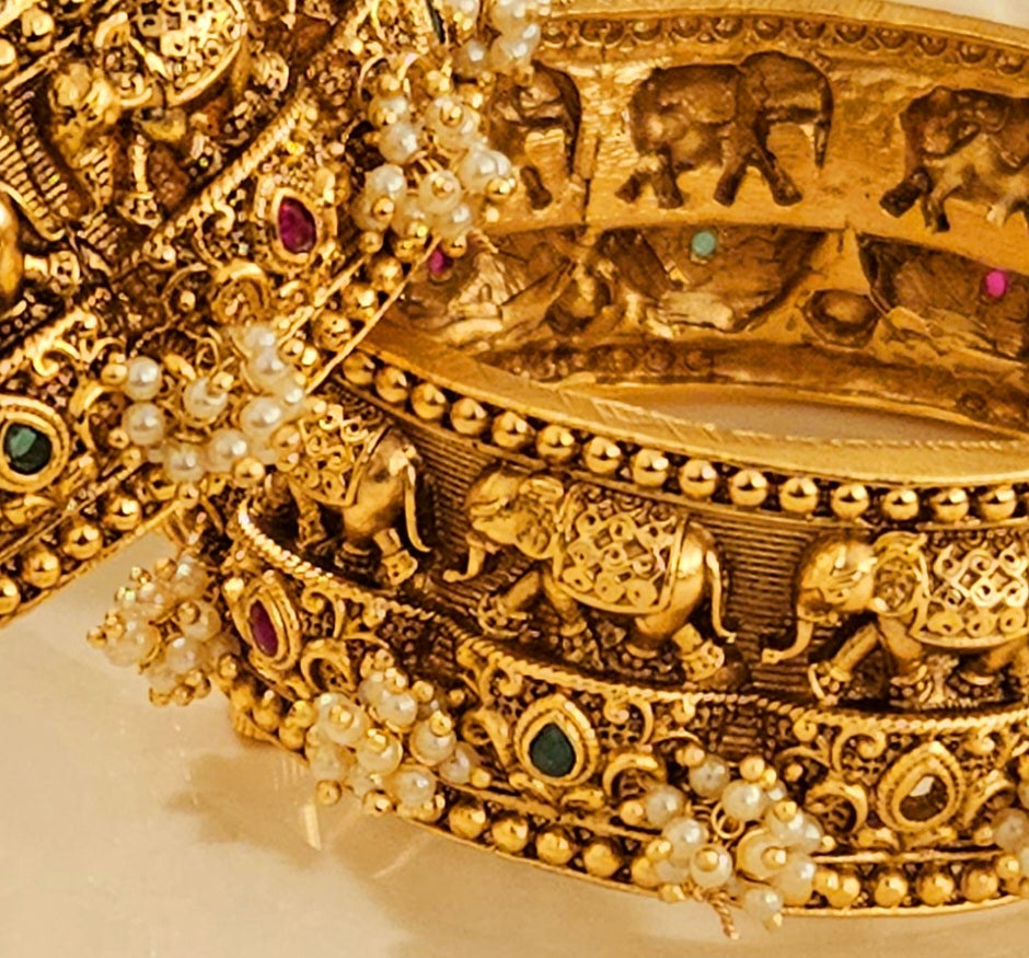 Gold finish broad kara (bangle) with marching elephants and pearl bead cluster (2 pcs)