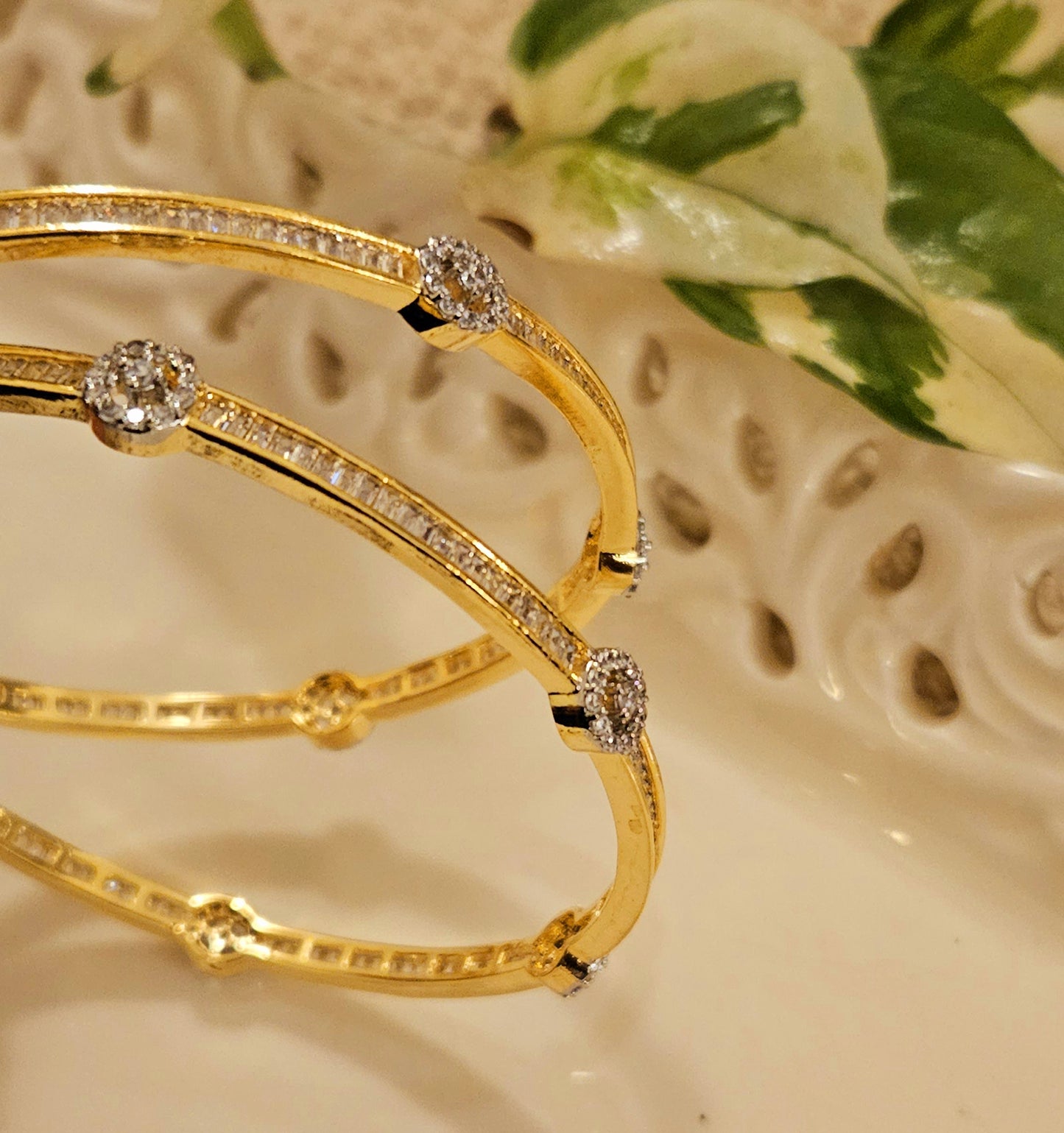 Gold finish sleek bangles with small cylindrical crystal and CZ flower design (2 pcs)