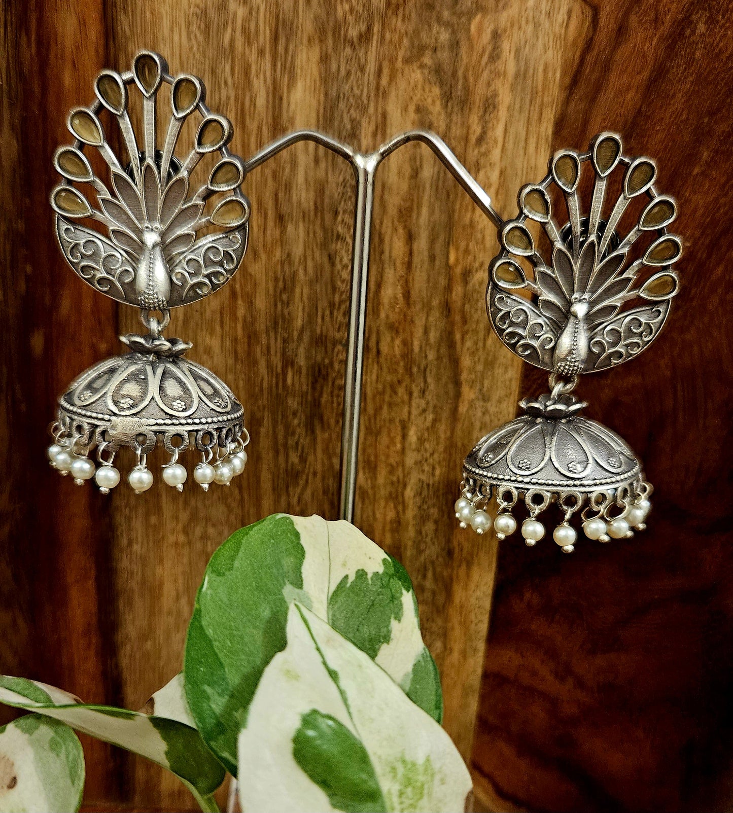 Silver finish jhumka (earrings) with peacock design stud and flat dome