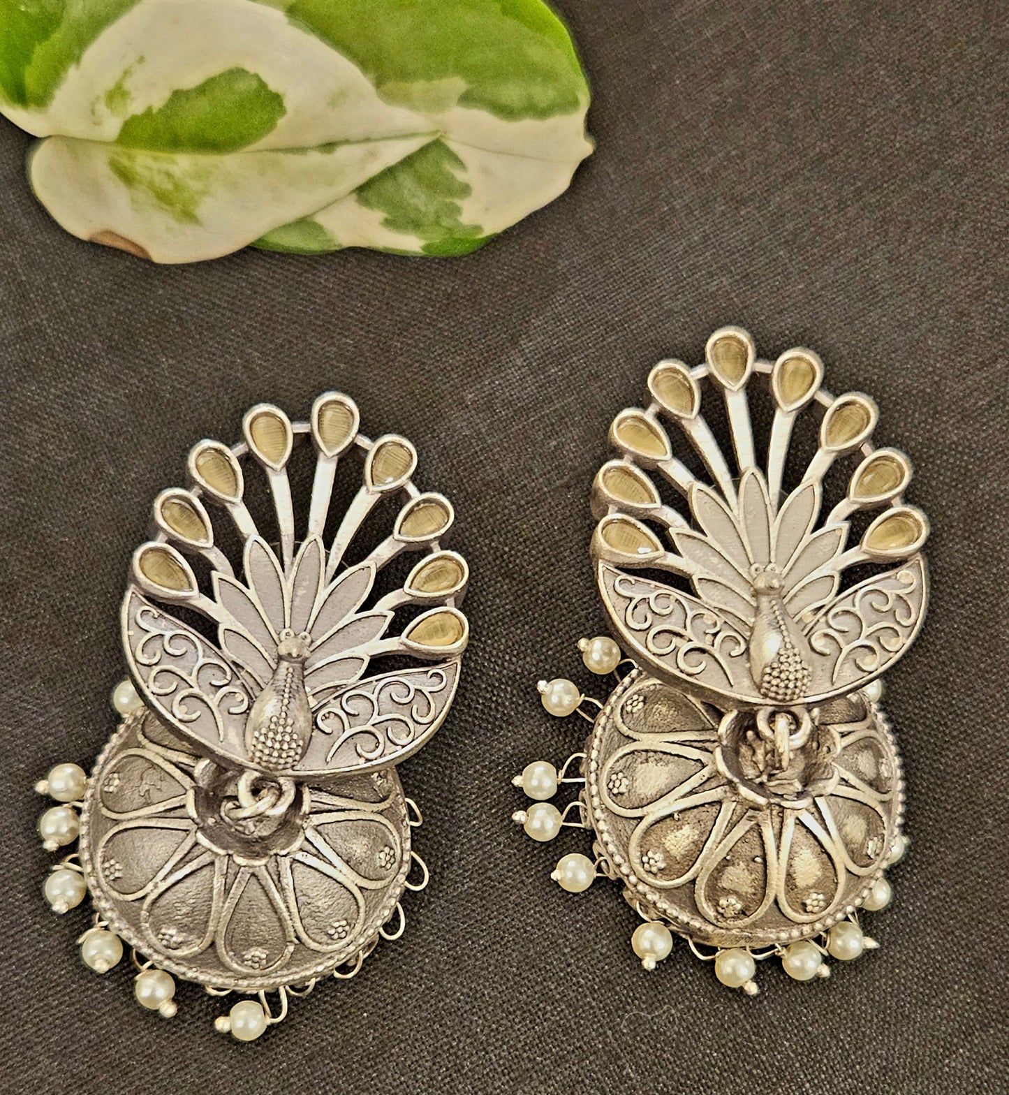 Silver finish jhumka (earrings) with peacock design stud and flat dome