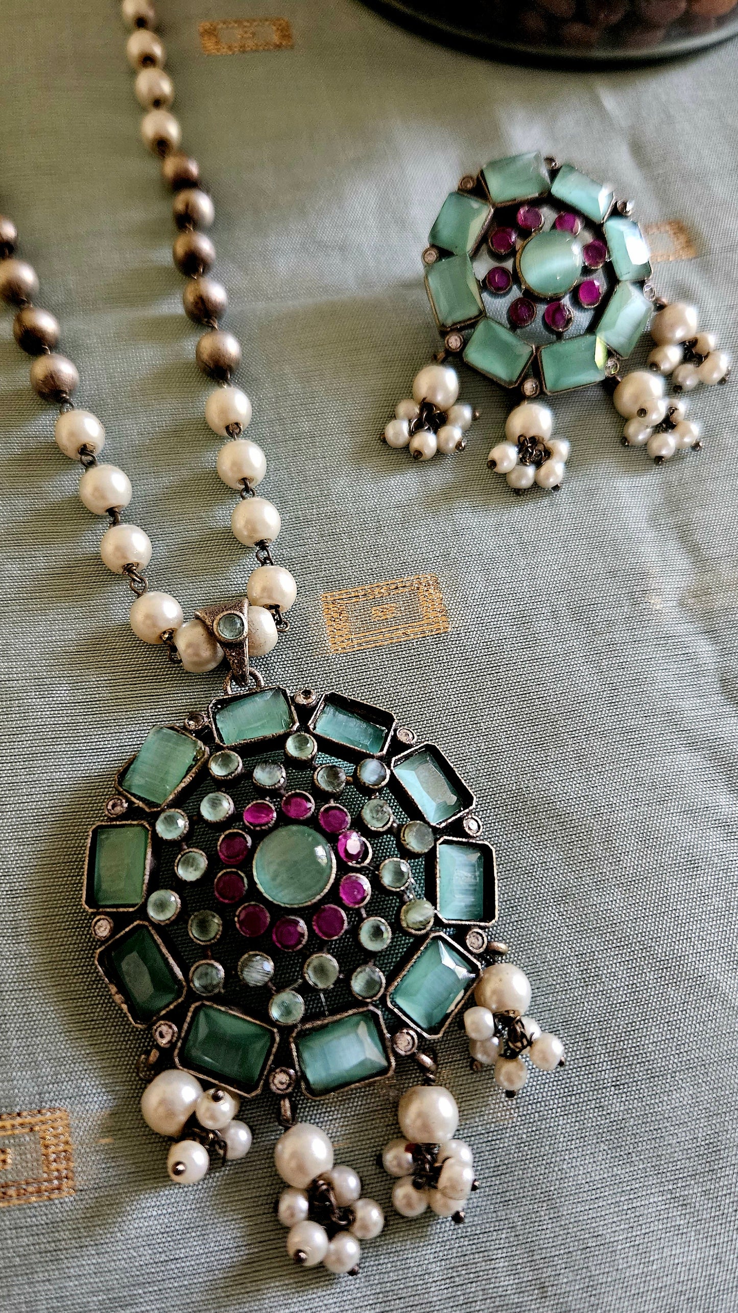 Silver finish long necklace set with big round pendant embellished with peach/green stones, matching studs (earrings)