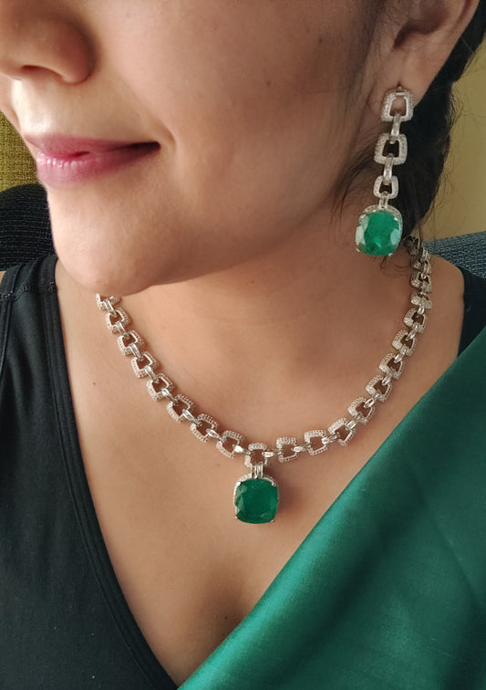 Platinum finish set, necklace in thick chain design with chunky emerald pendant, matching earrings